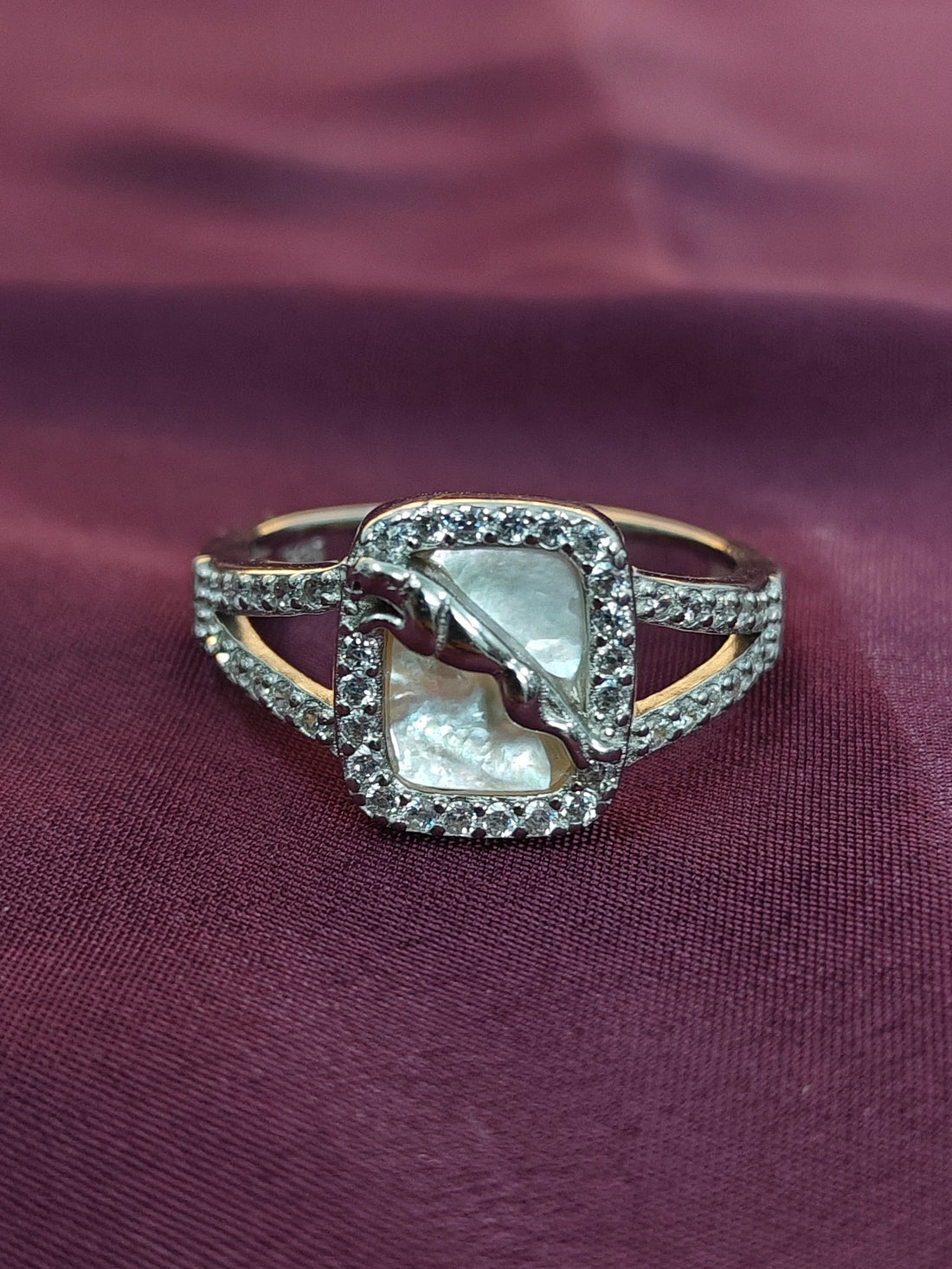 Ring with a central pearl and diamond accents on a purple fabric background