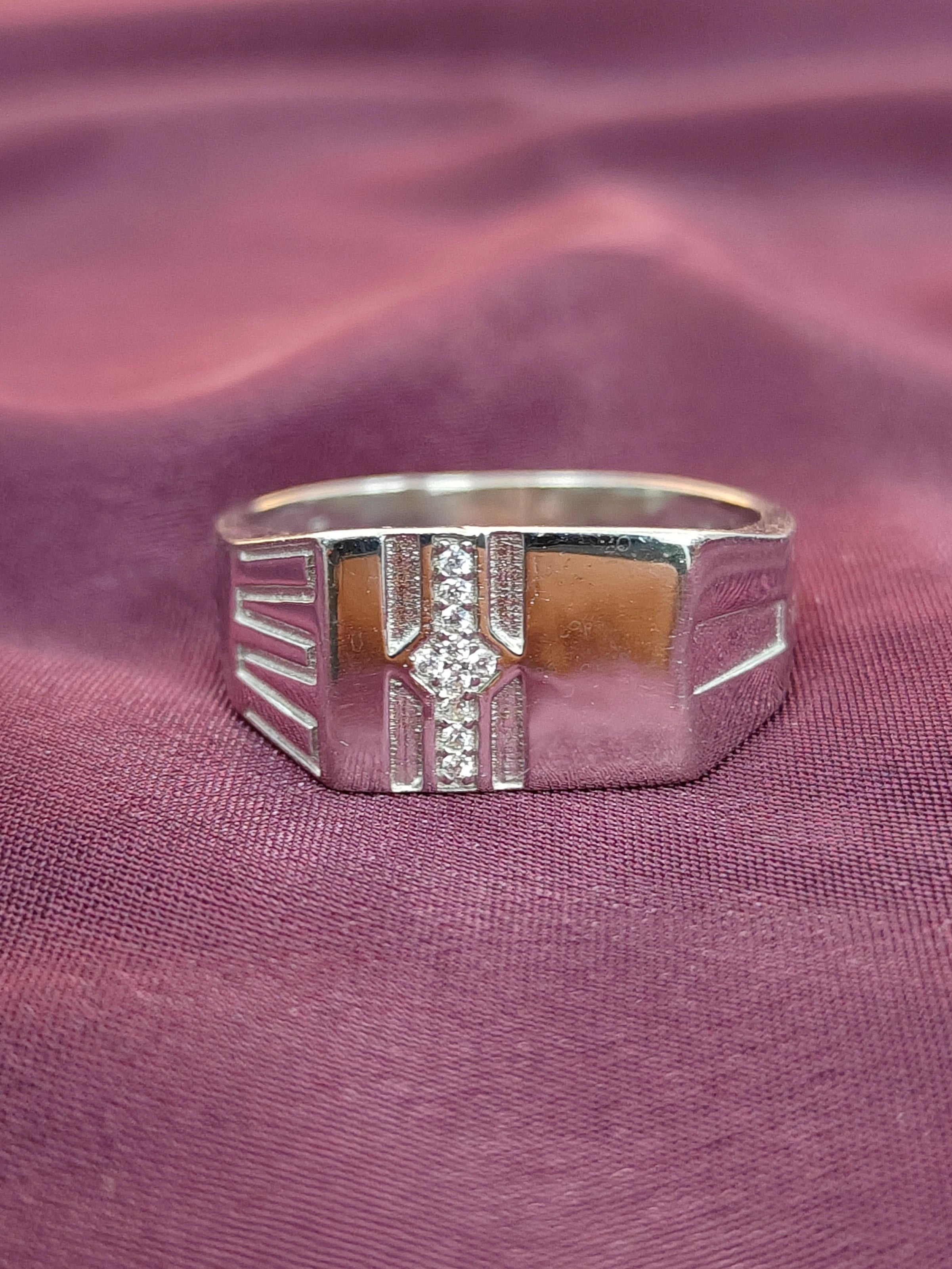 Silver ring with a diamond on a purple fabric background