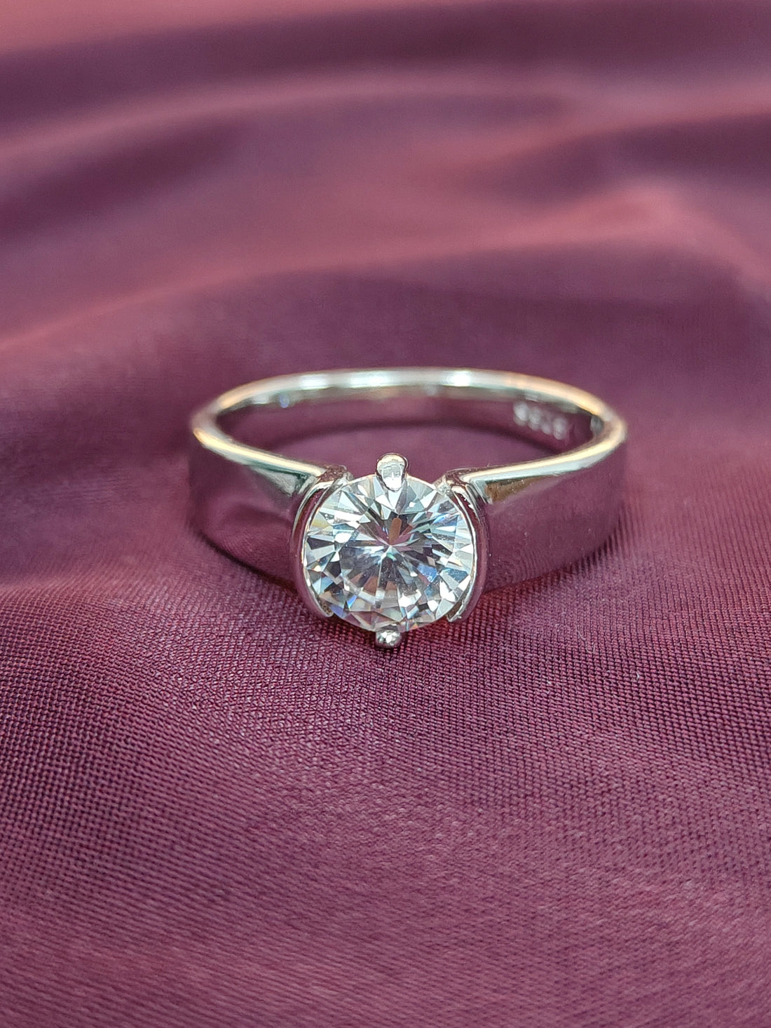 Gold ring with a diamond on a purple fabric background