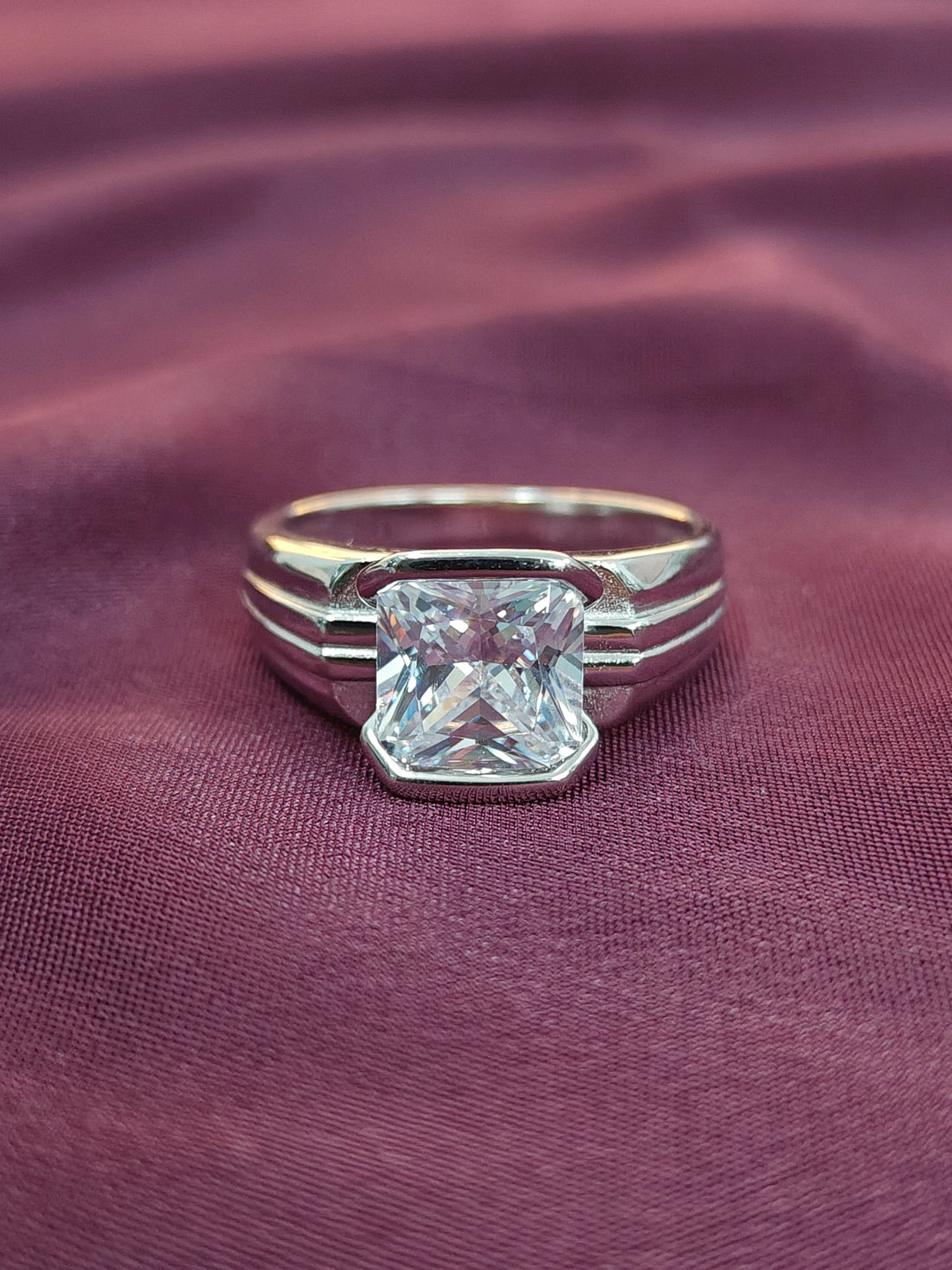 Silver ring with a large diamond on a purple fabric background