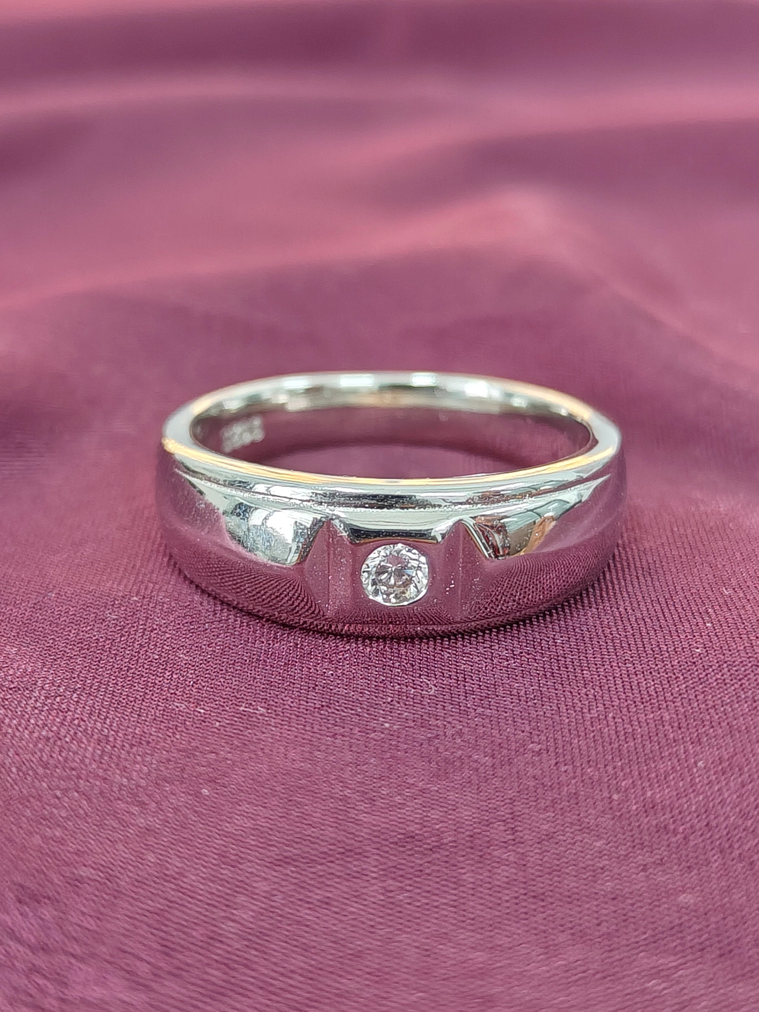 Silver ring with a diamond on a purple fabric background