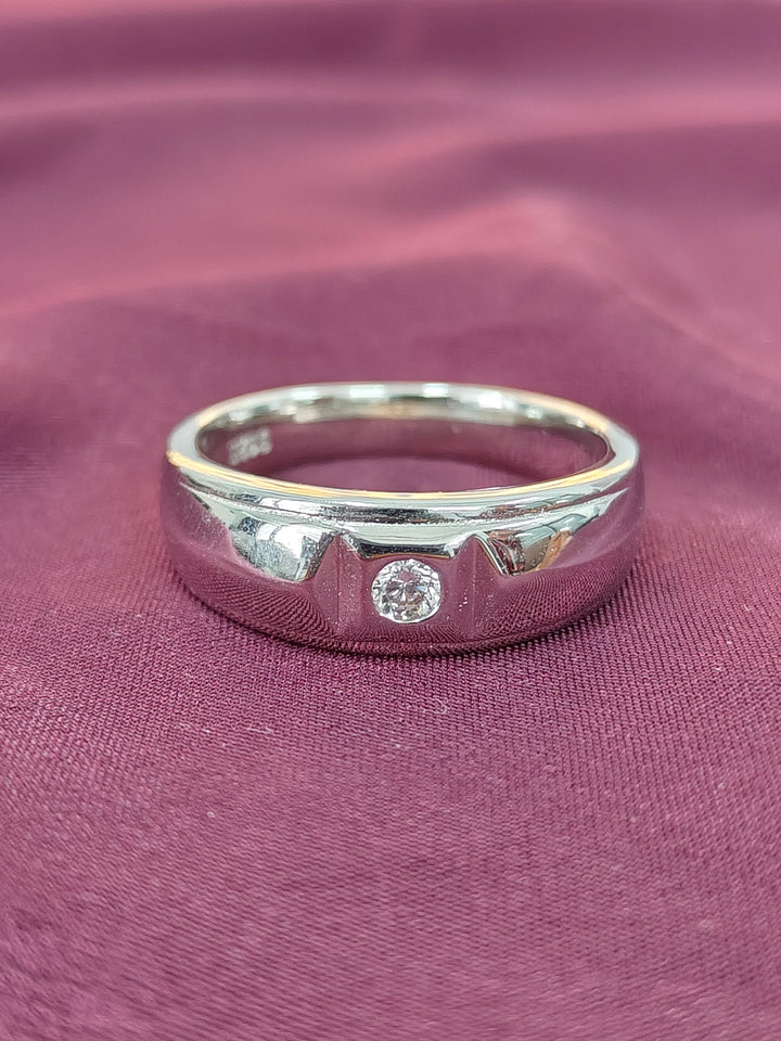 Silver ring with a diamond on a purple fabric background