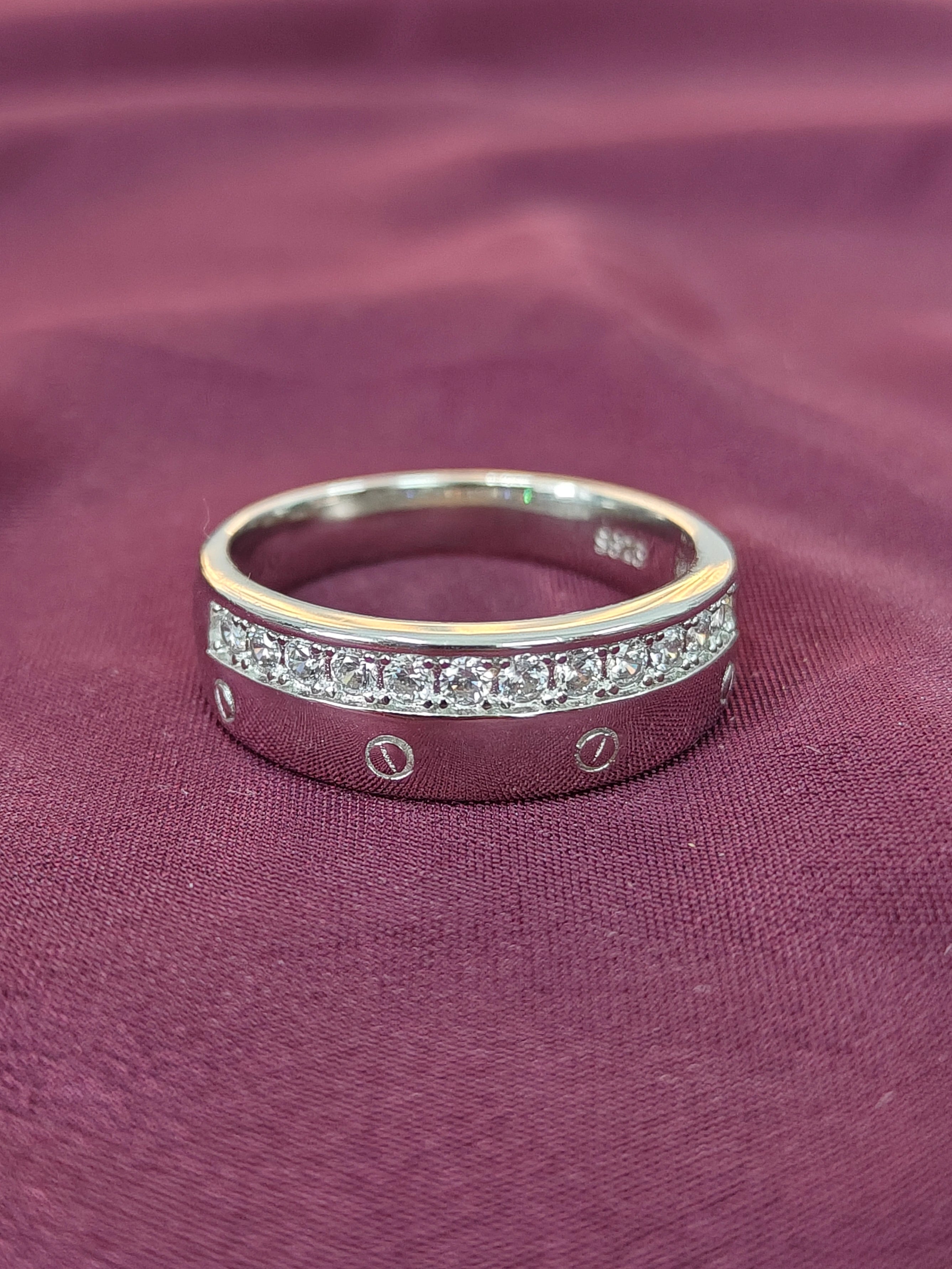 Silver ring with embedded stones on a purple fabric background