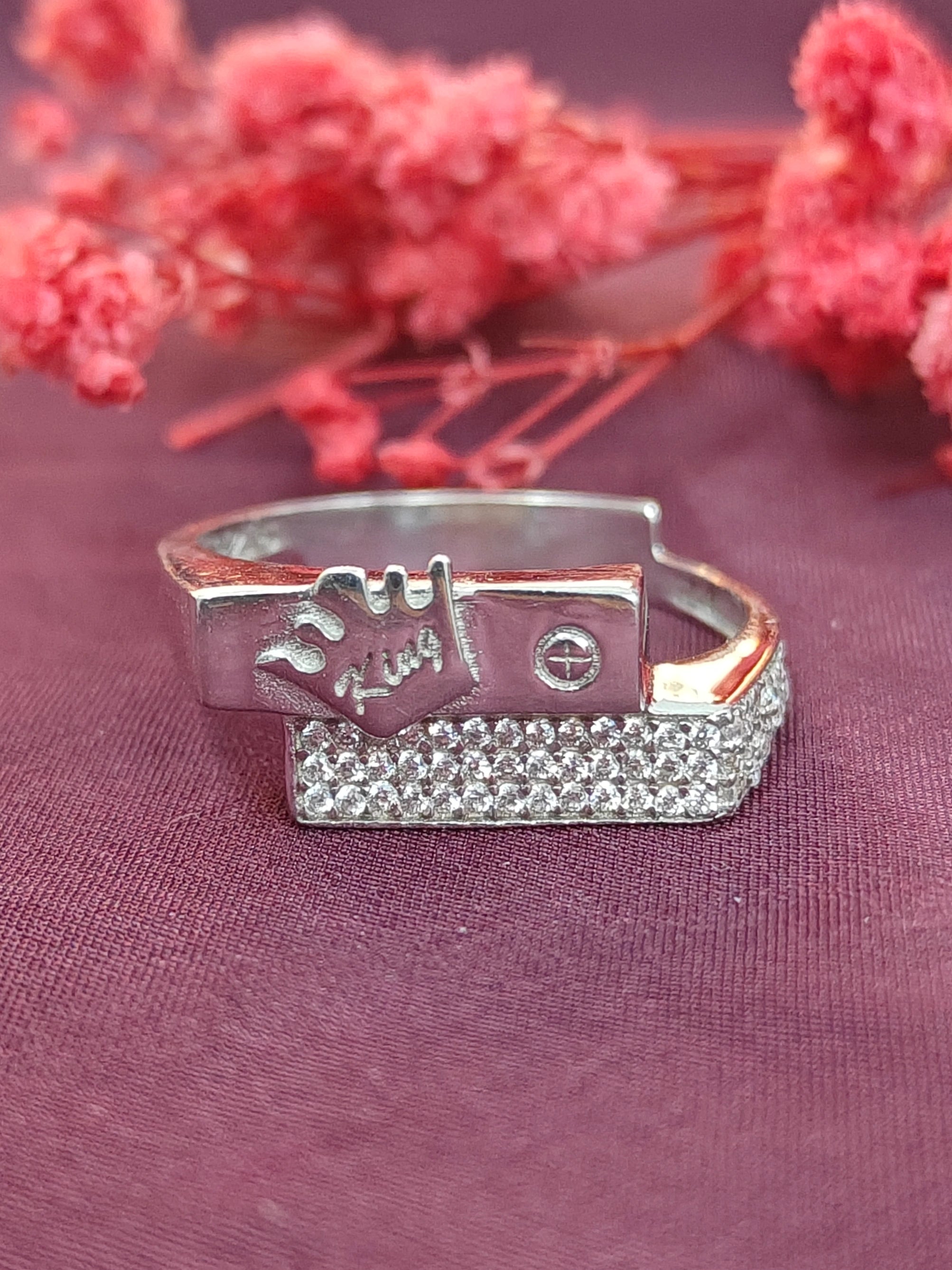 Silver ring with engraved design on a purple fabric background