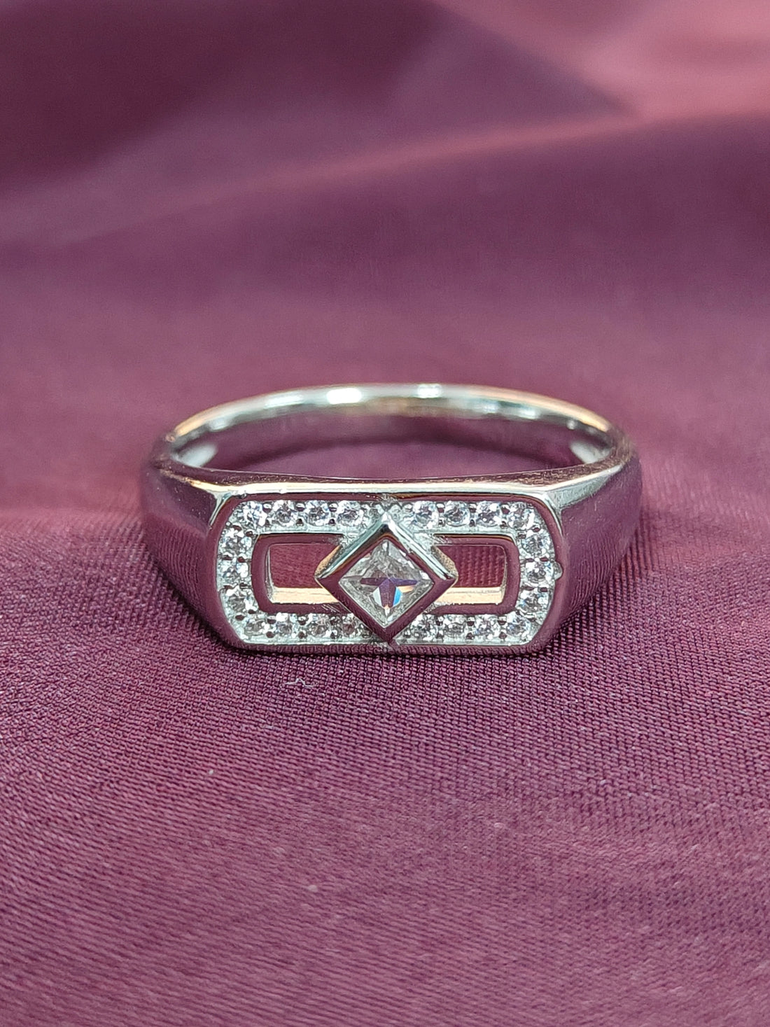 Silver ring with diamond on a purple fabric background