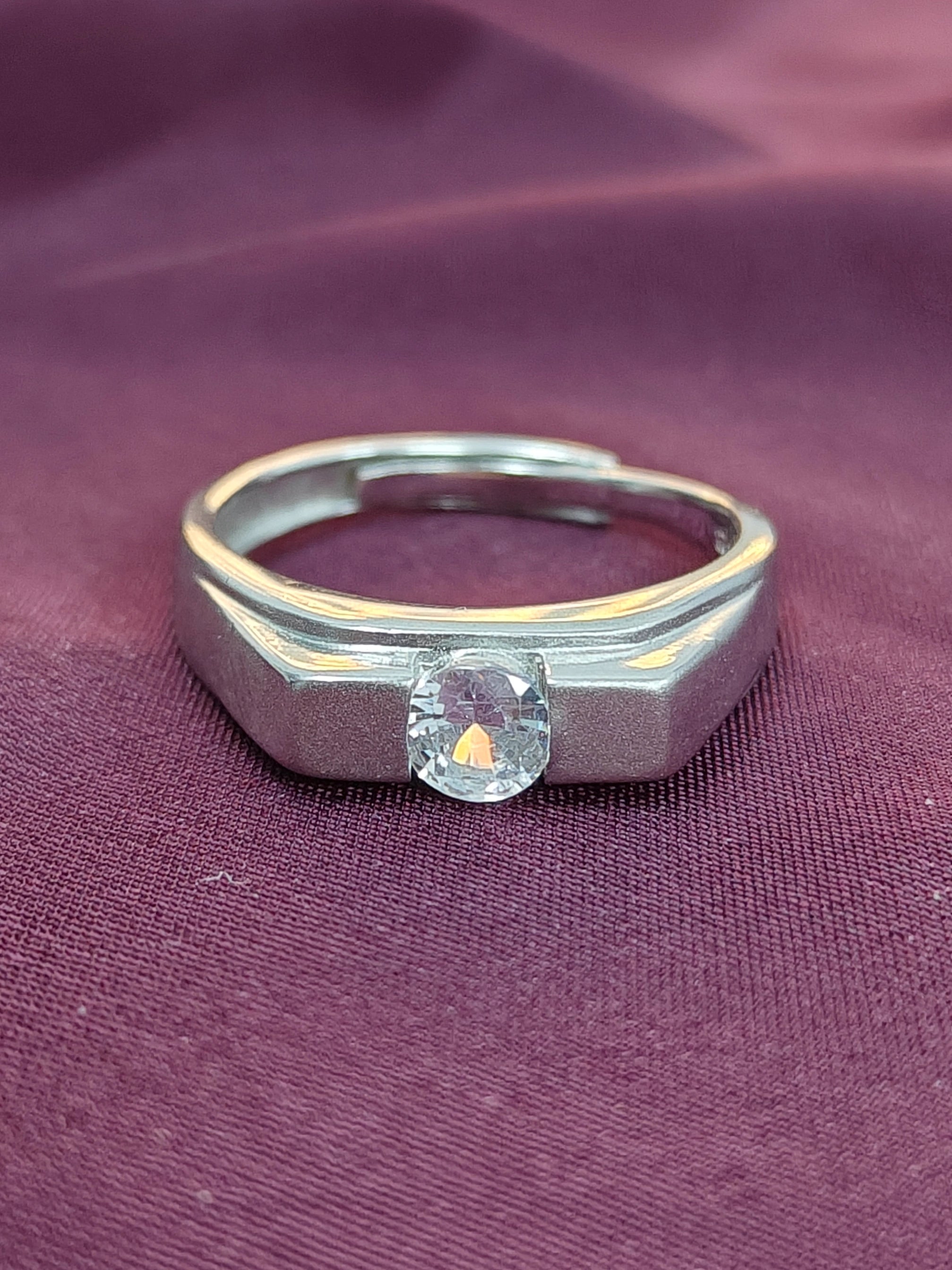 Silver ring with a diamond on a purple fabric background