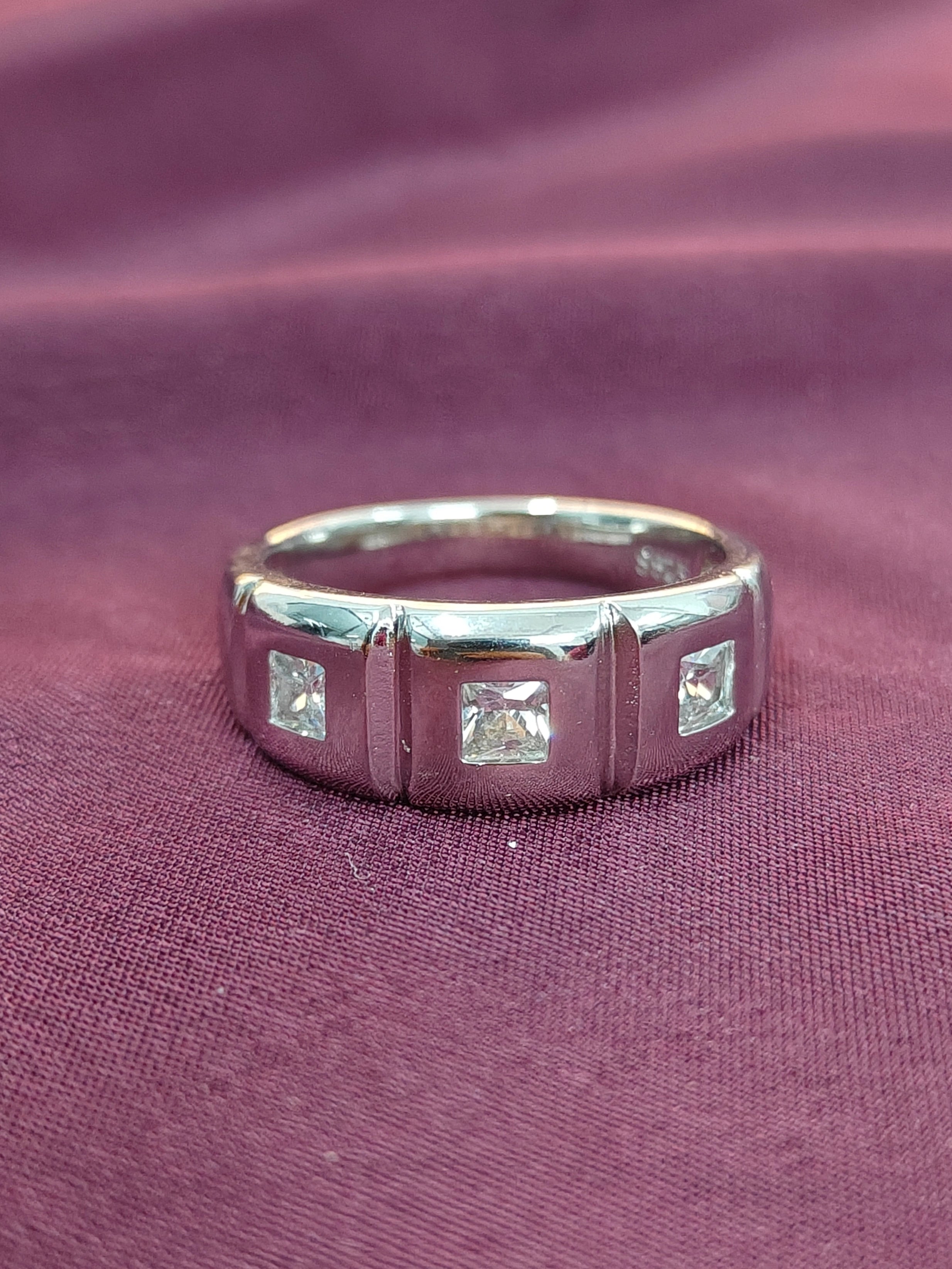 Silver ring with square-cut diamonds on a purple fabric background