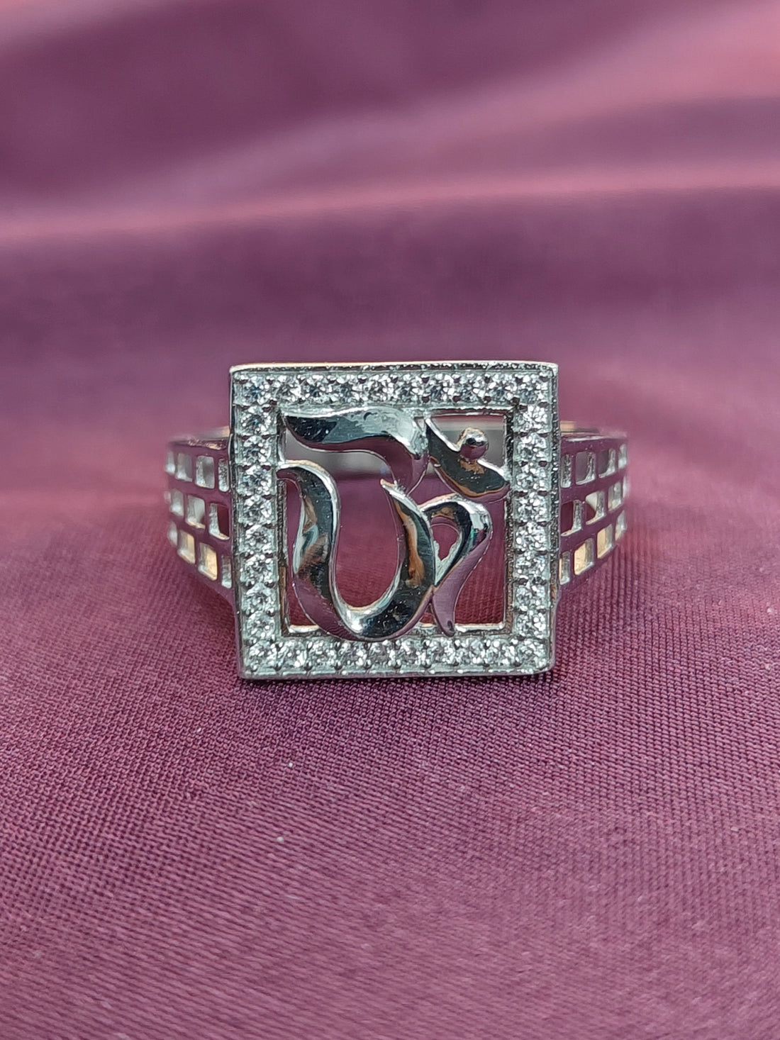 Silver ring with dolphin design on a purple fabric background