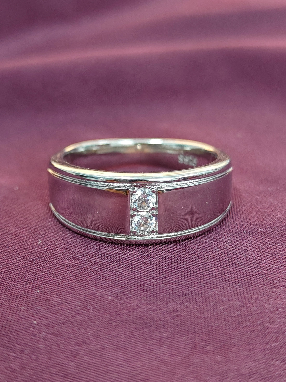 Silver ring with diamonds on a purple fabric background
