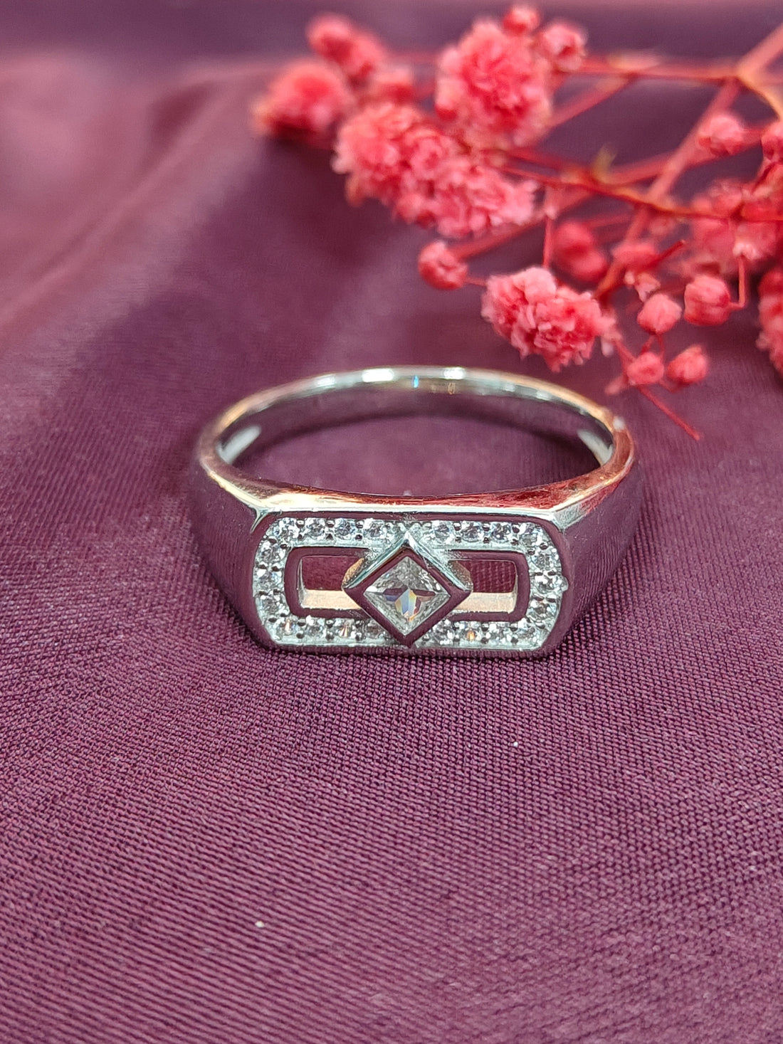Silver ring with diamond on a purple fabric background