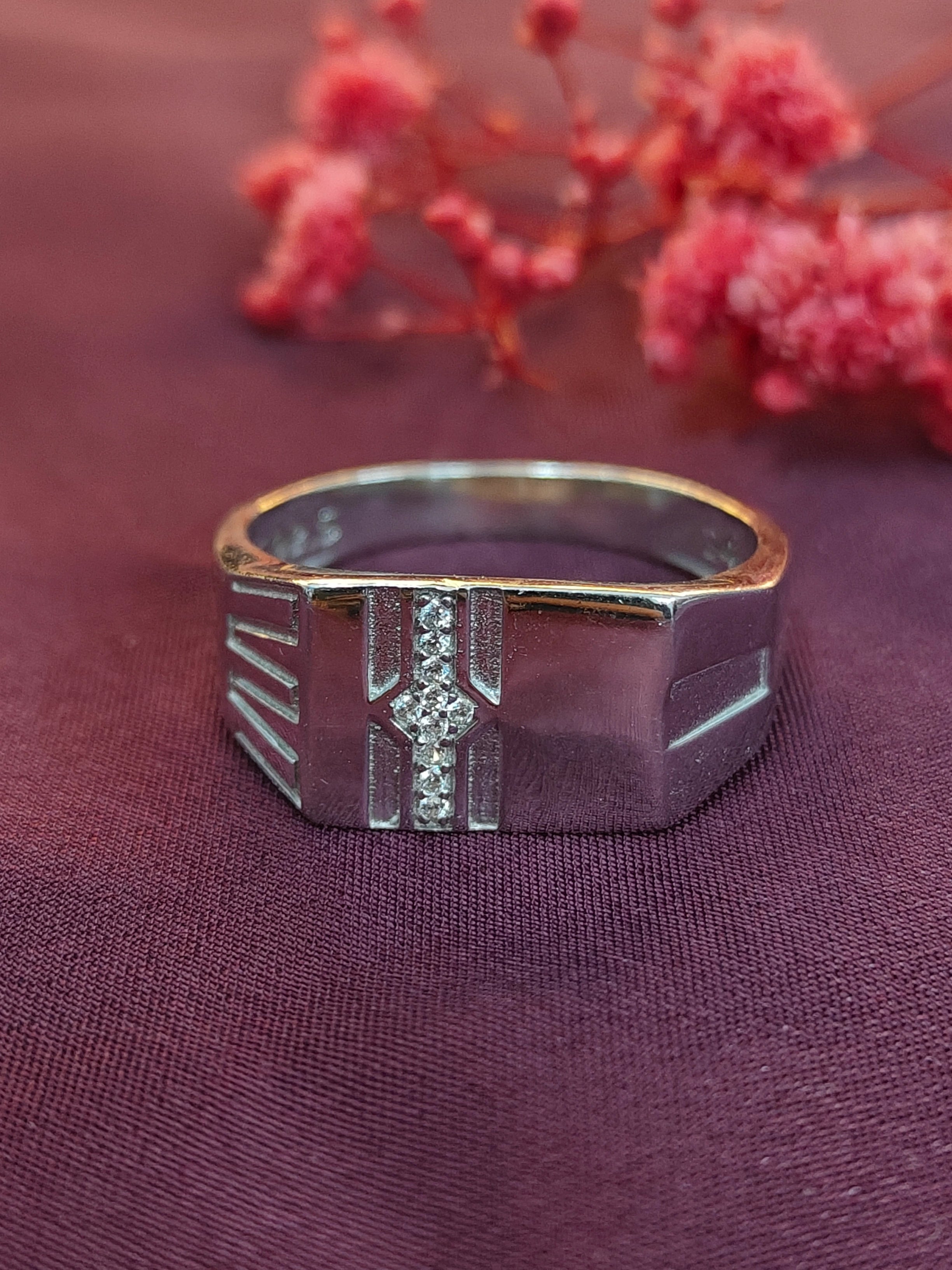 Silver ring with a diamond on a purple fabric background