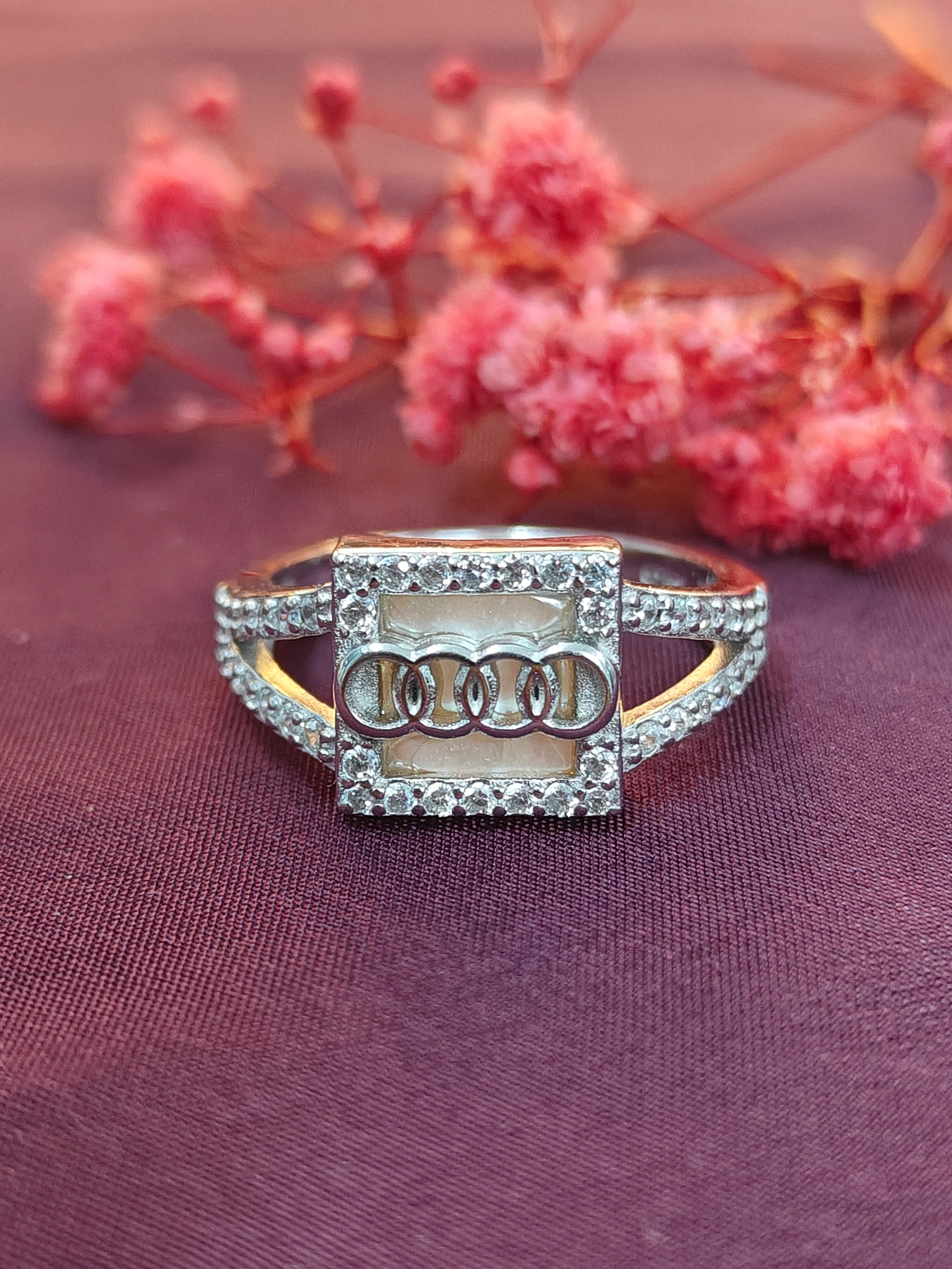 Gold and diamond ring on a purple fabric background with pink flowers.