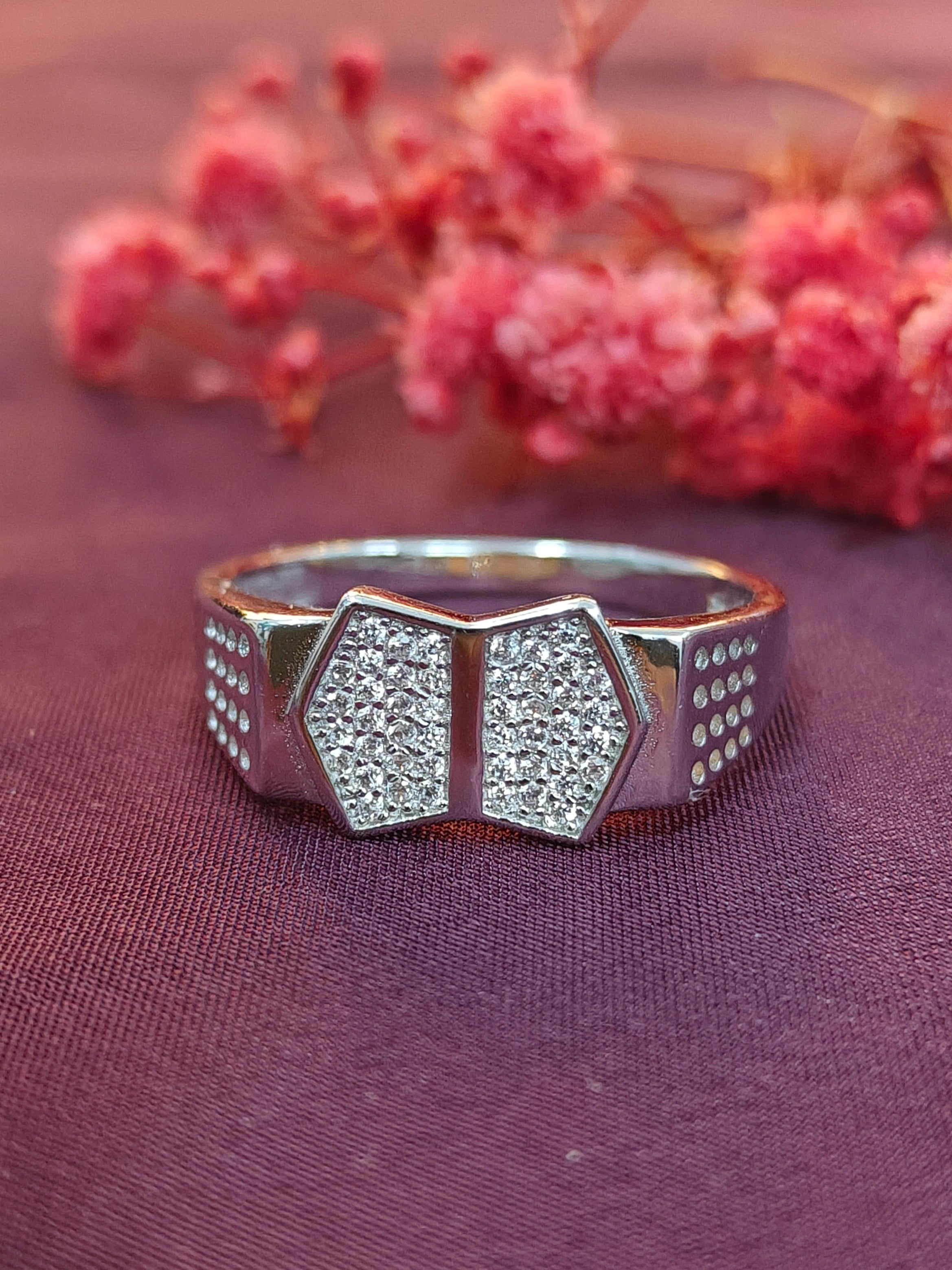 Silver ring with geometric design on a purple fabric background