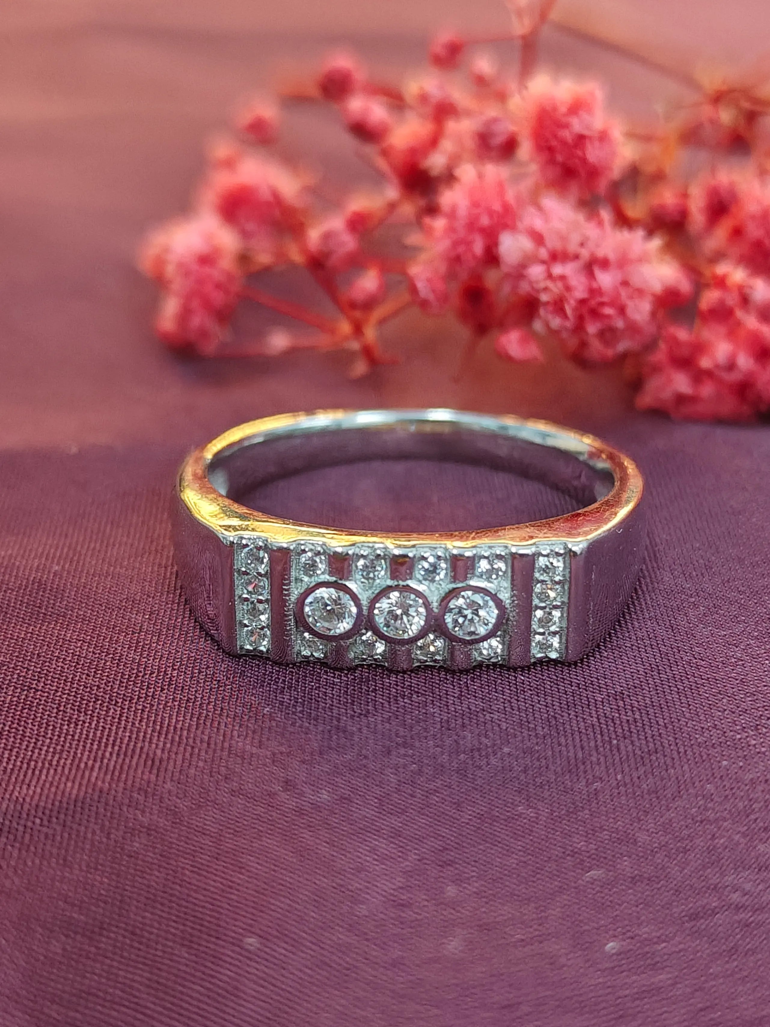 Gold ring with embedded diamonds on a purple fabric background with pink flowers.