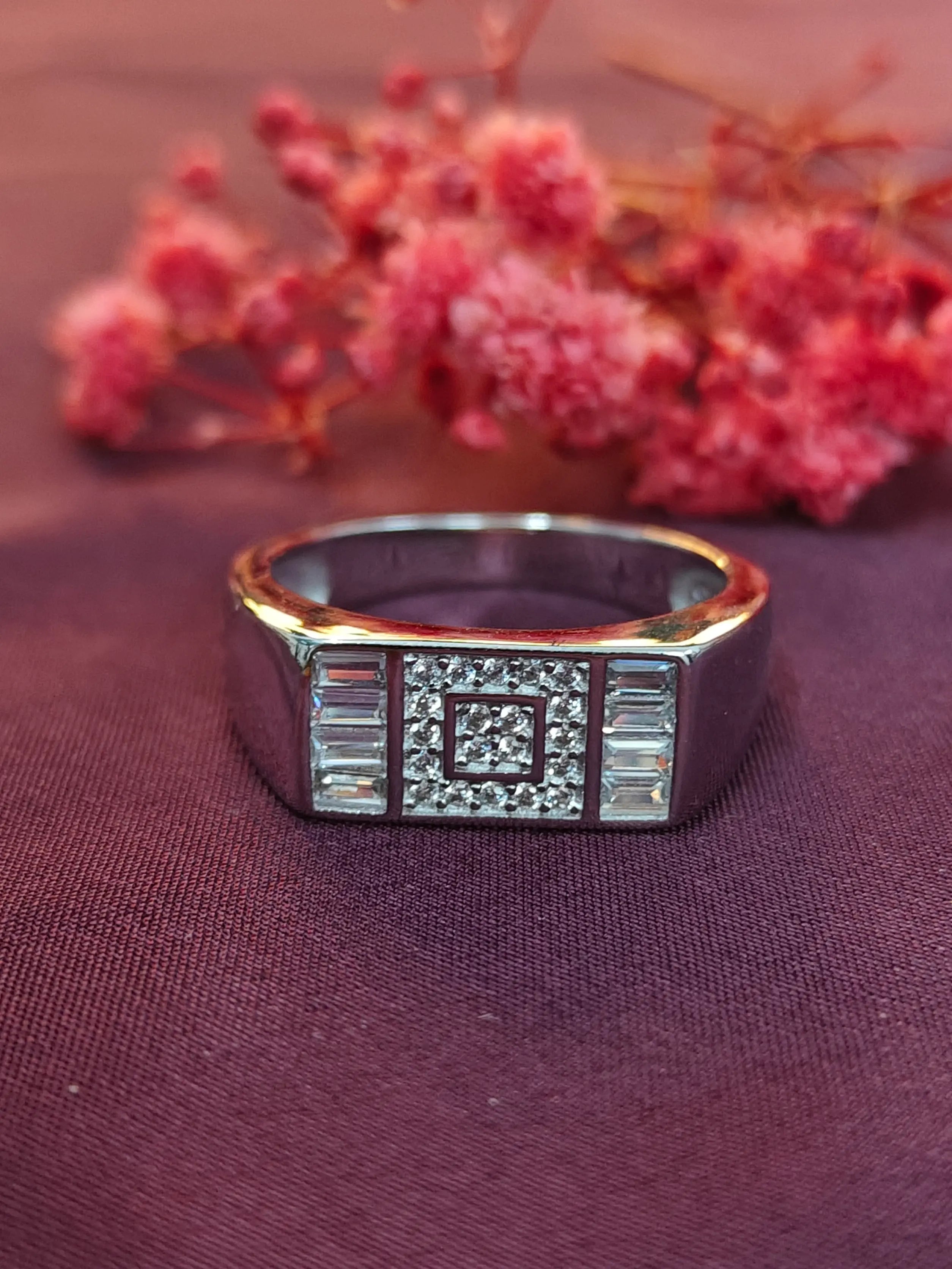 Gold ring with diamond accents on a purple fabric background with pink flowers.