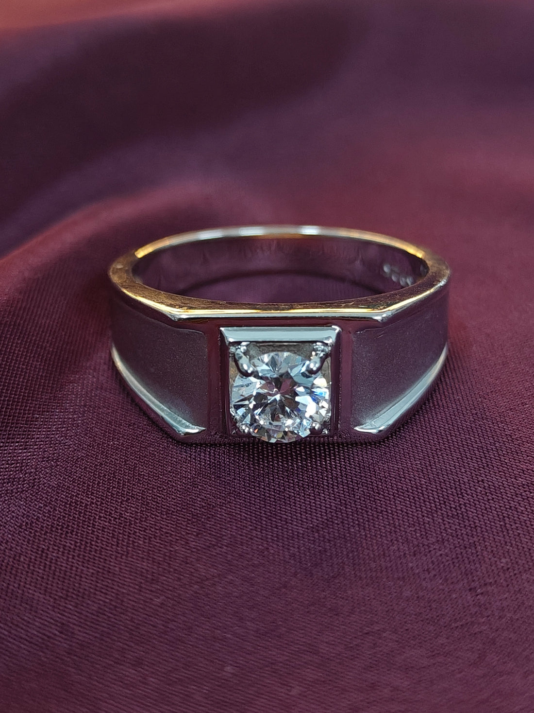 Gold and silver ring with a diamond on a purple fabric background