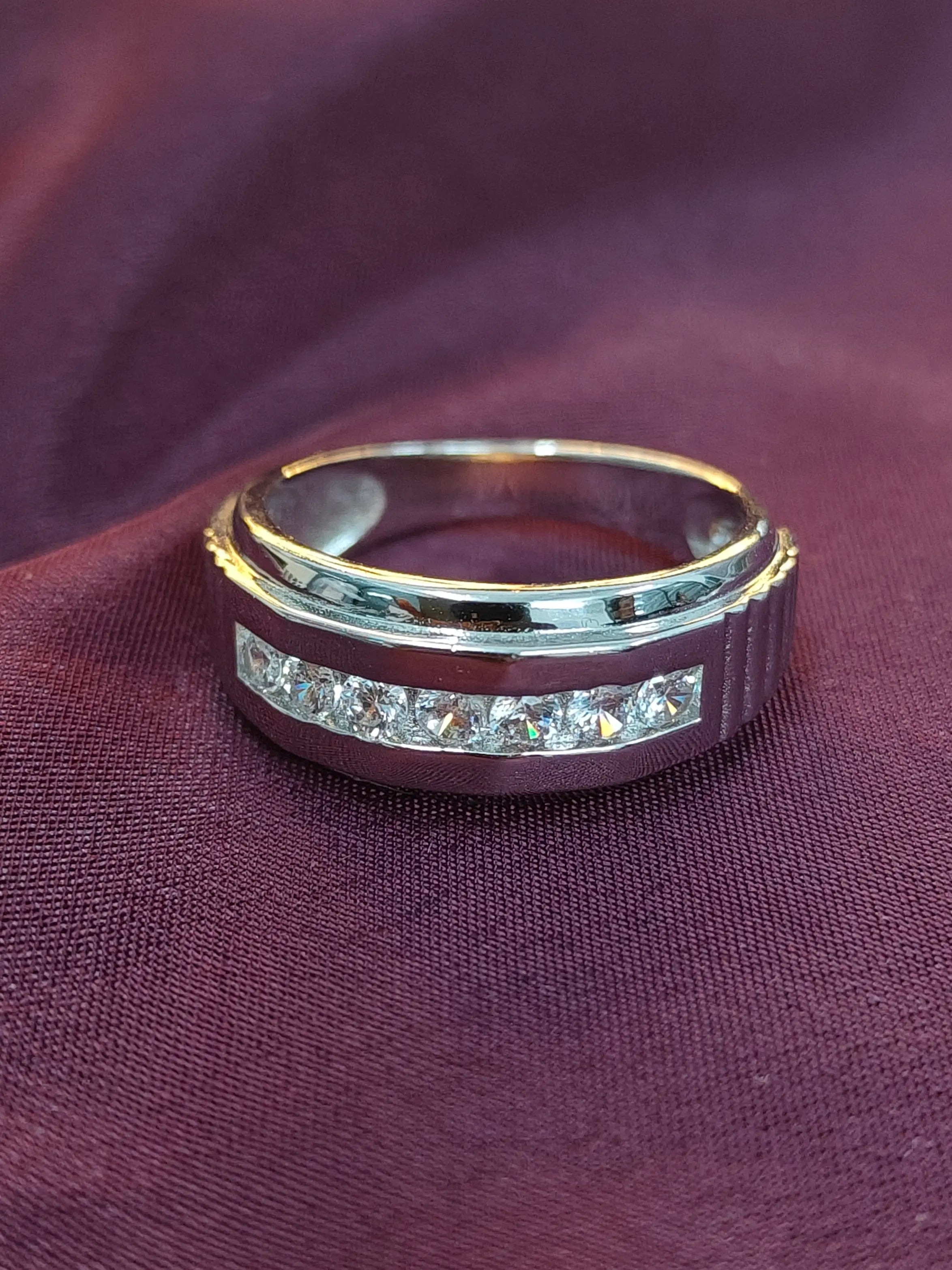 Gold and silver ring with embedded stones on a purple fabric background
