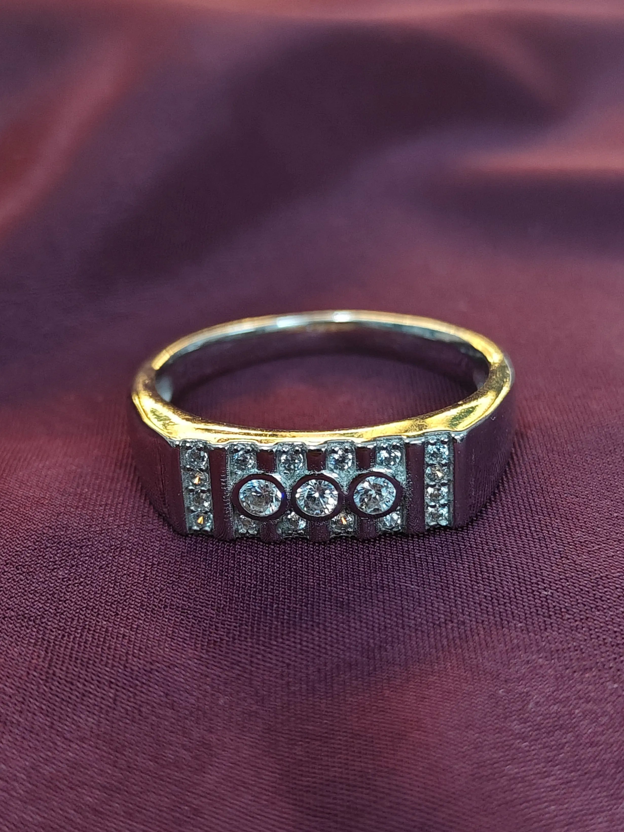 Gold ring with embedded stones on a maroon fabric background