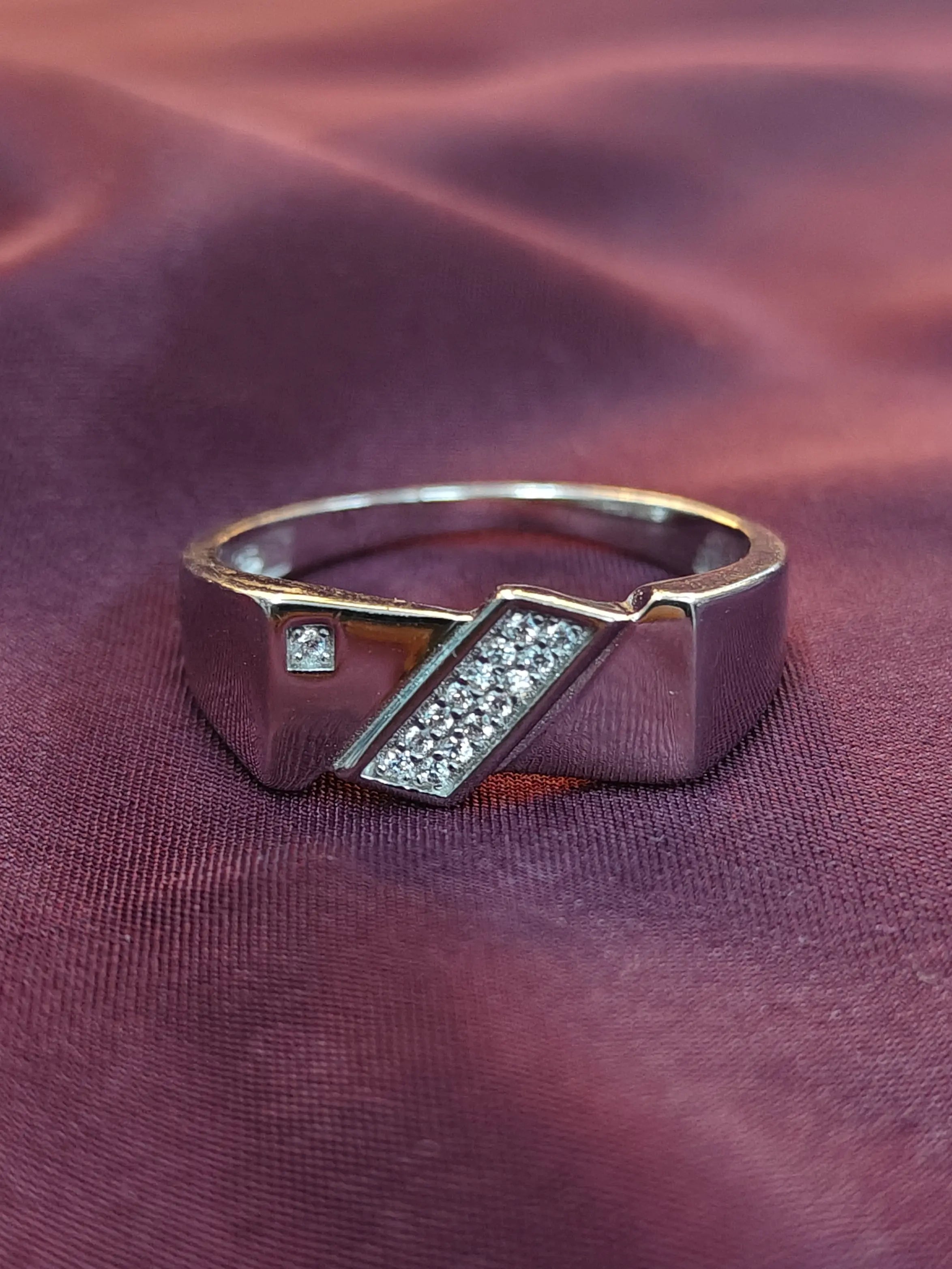 Silver ring with diamond accents on a purple fabric background