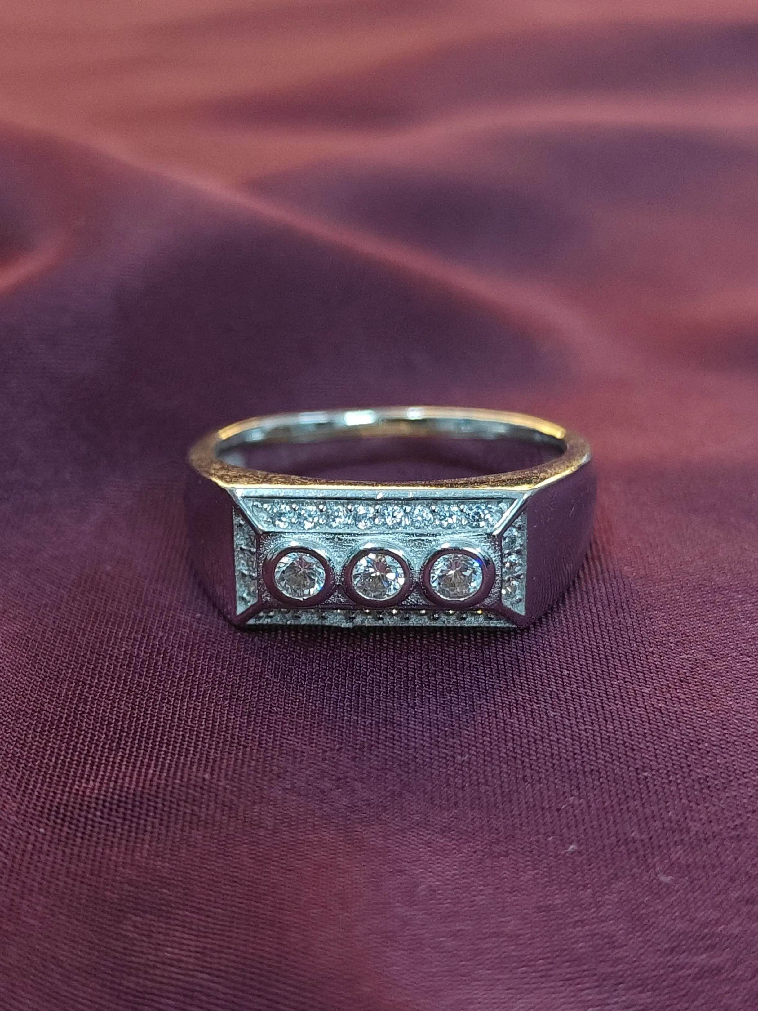 Ring with three diamonds on a maroon fabric background