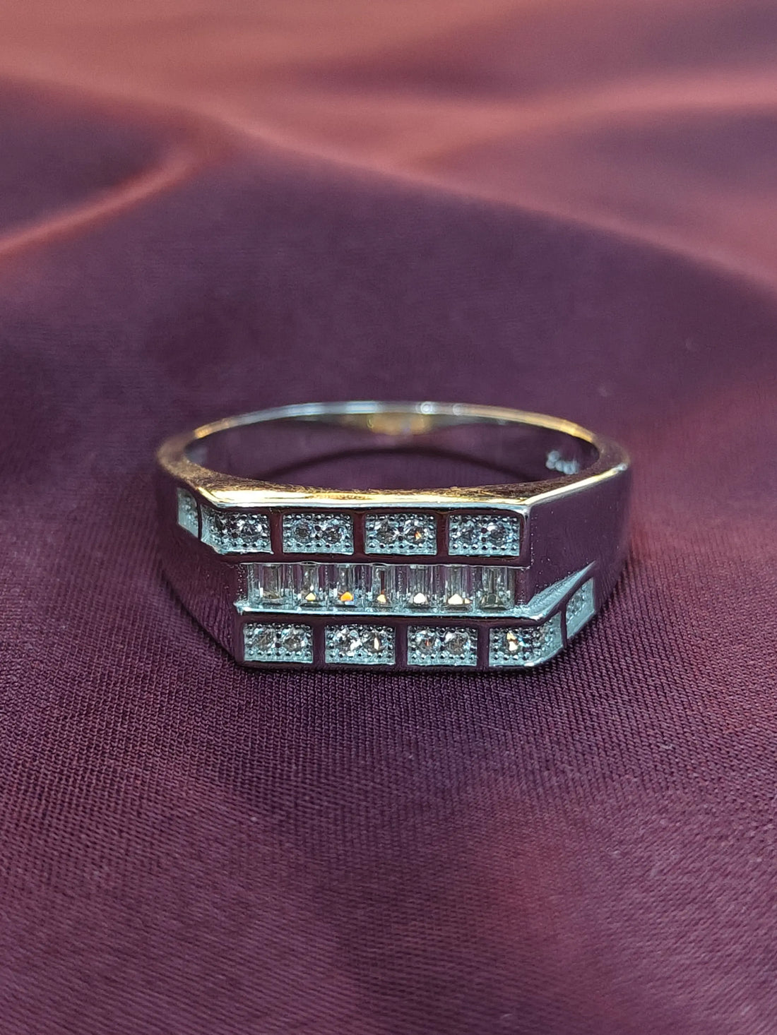 Silver ring with gemstones on a purple fabric background