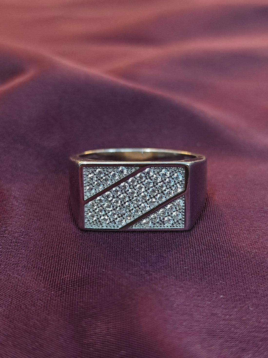 Gold ring with diamond accents on a purple fabric background