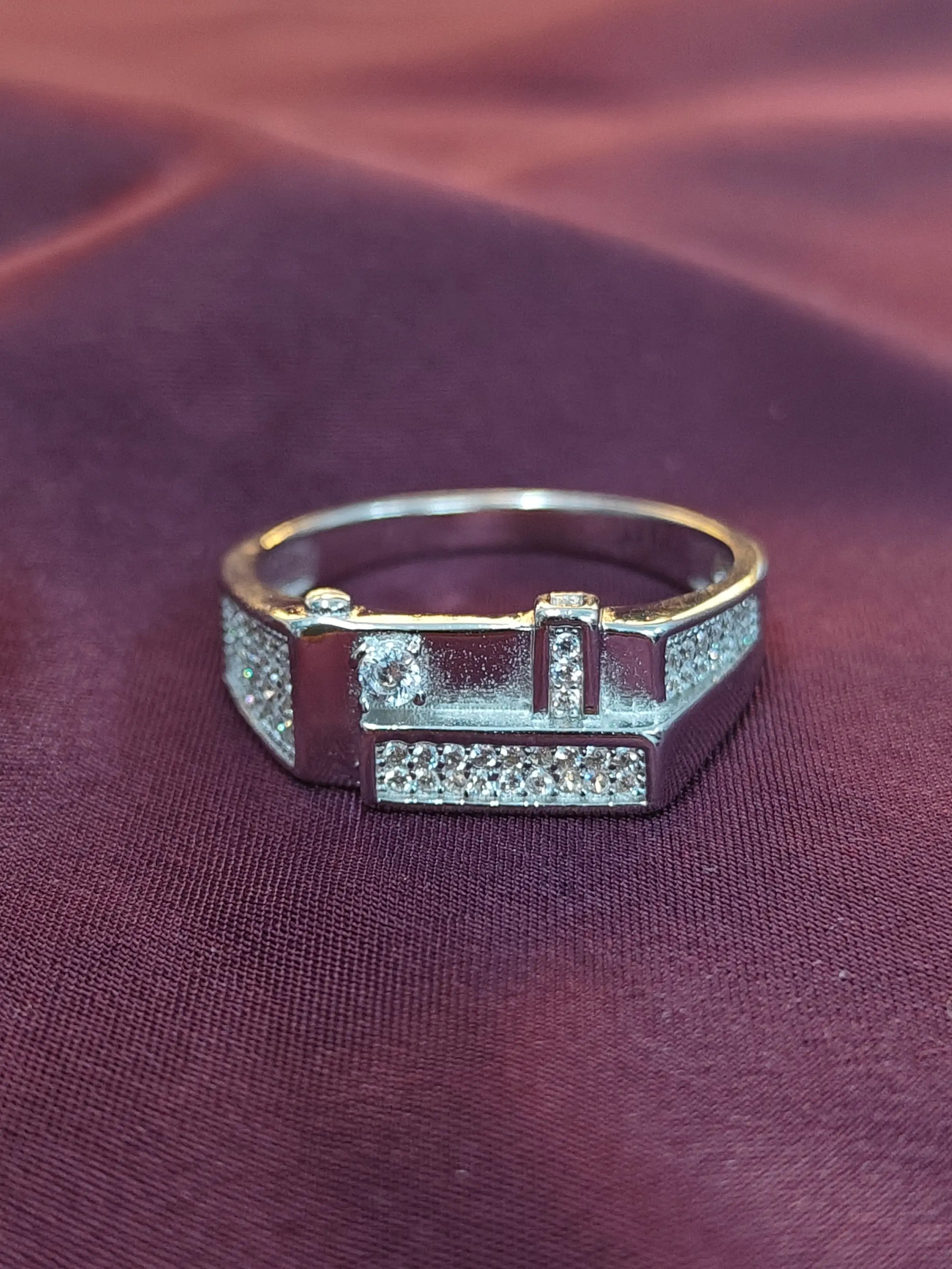 Silver ring with gemstones on a maroon fabric background