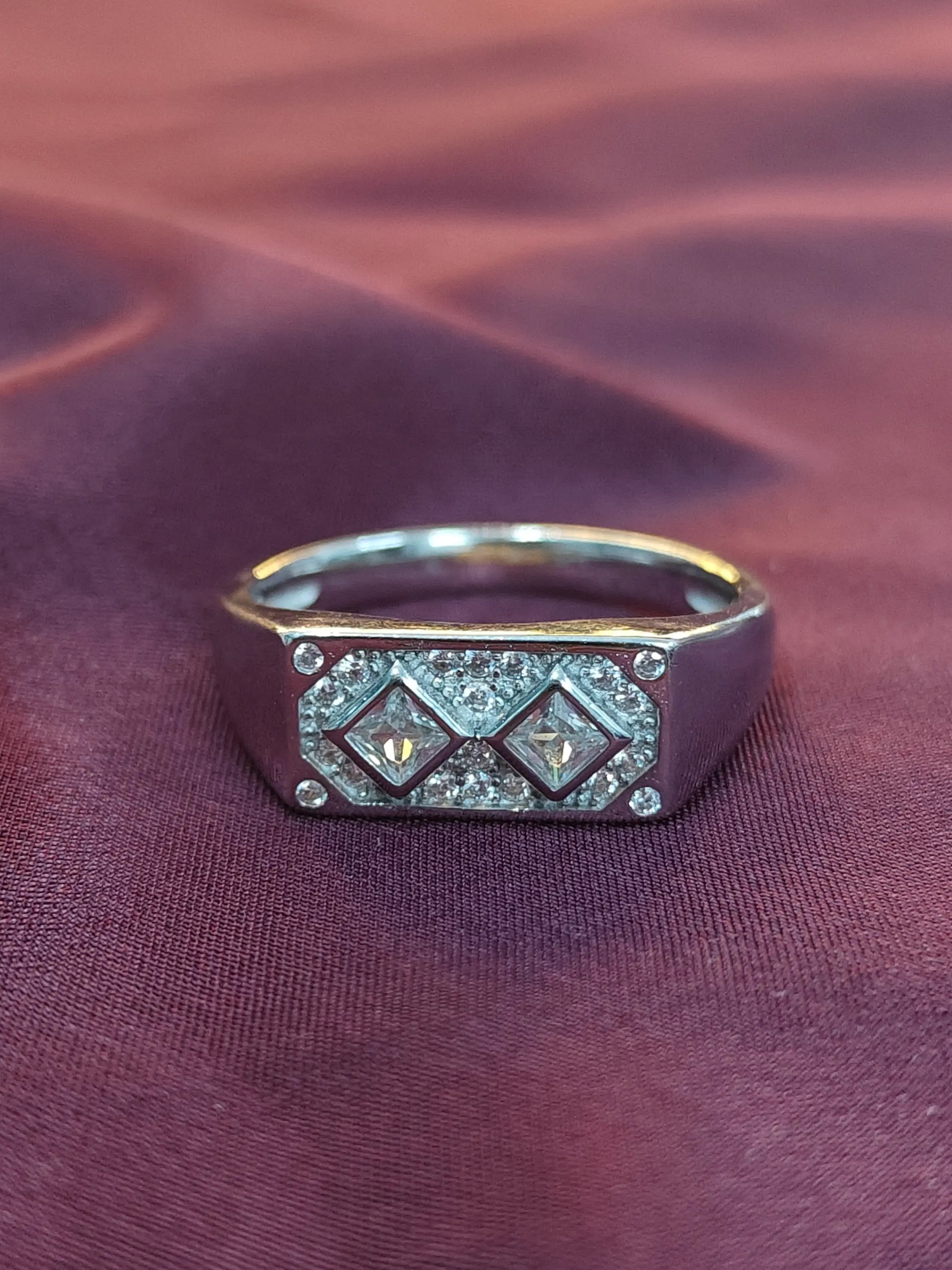 Silver ring with gemstones on a maroon fabric background