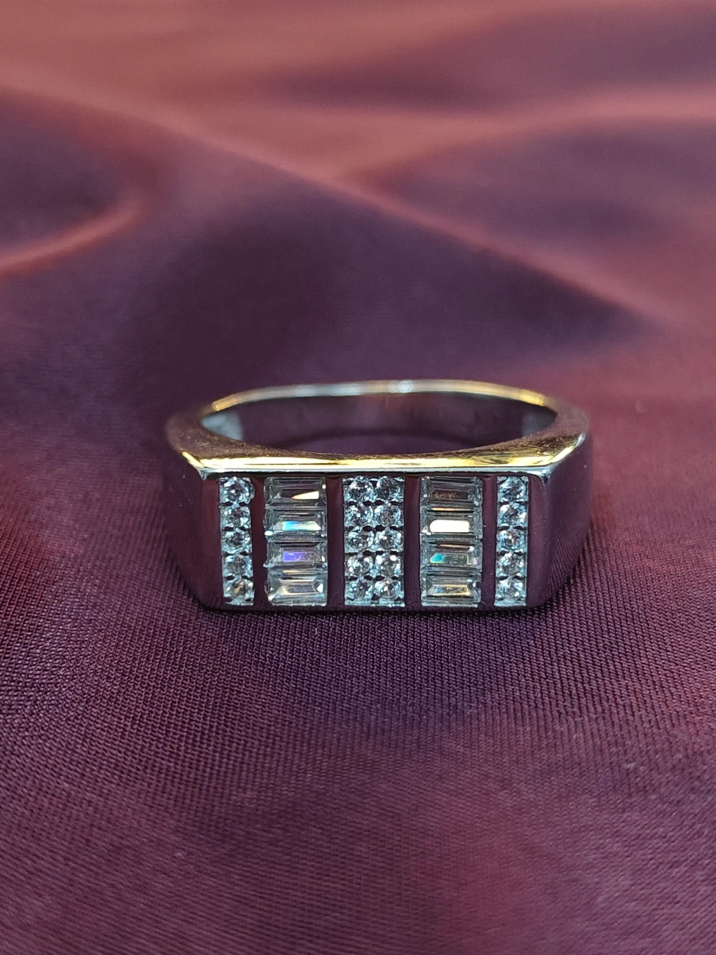 Gold ring with gemstones on a purple fabric background