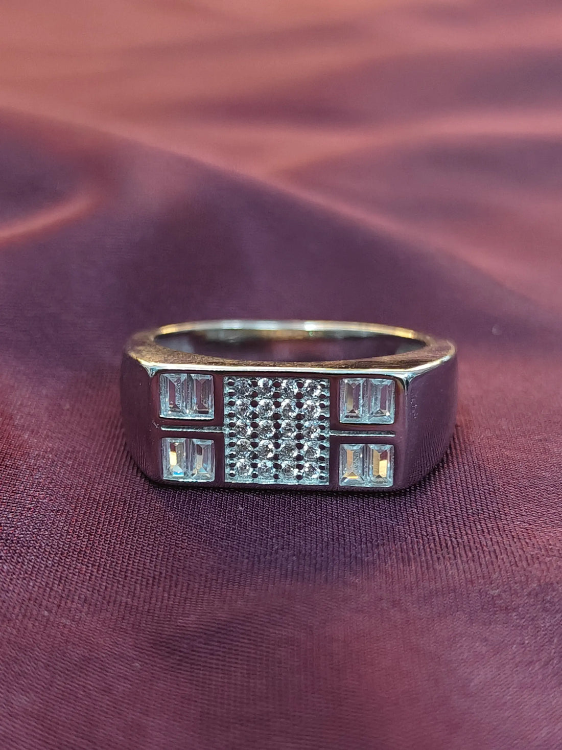 Silver ring with gemstones on a maroon fabric background