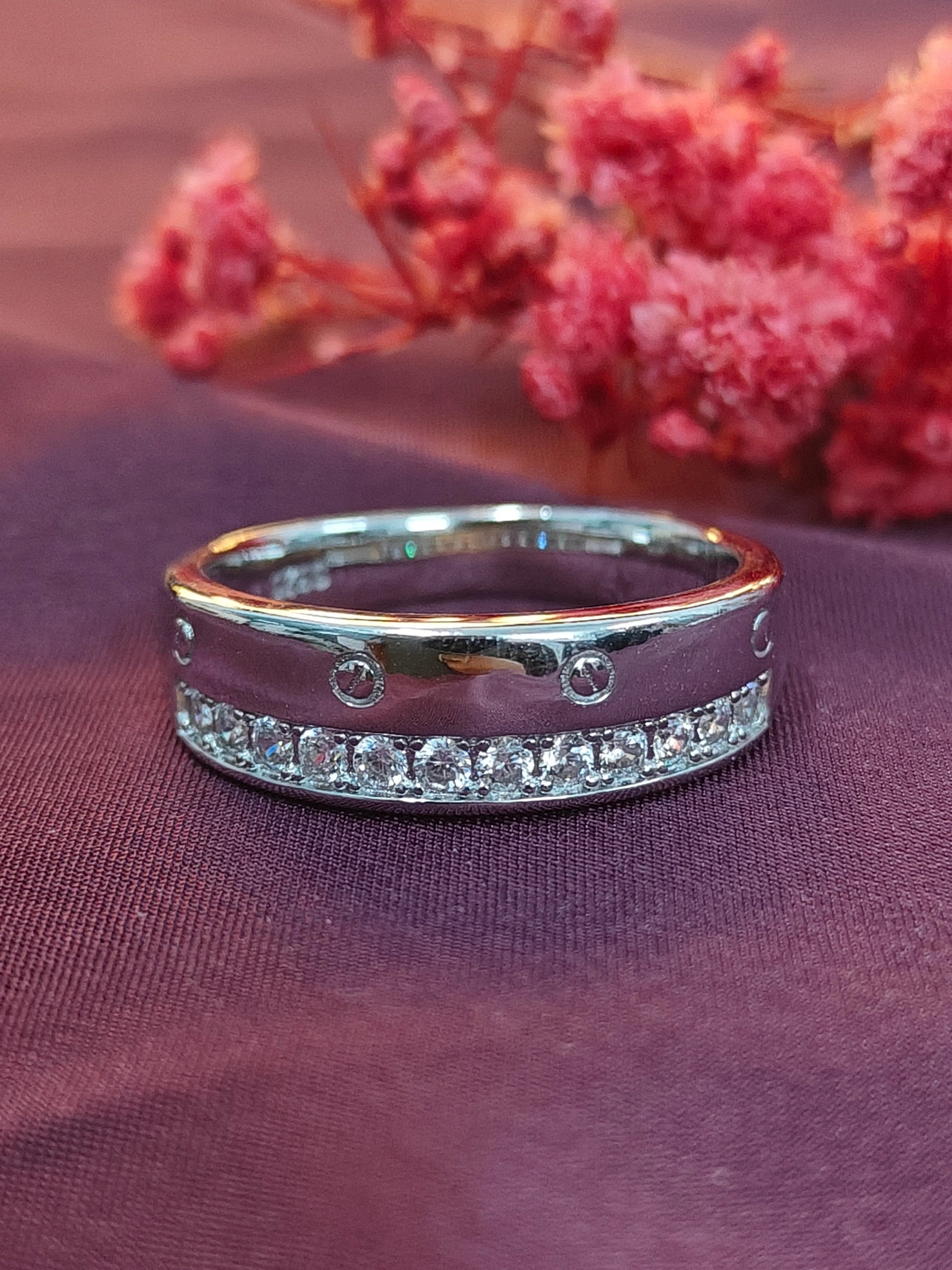 Silver ring with small diamonds on a purple fabric background