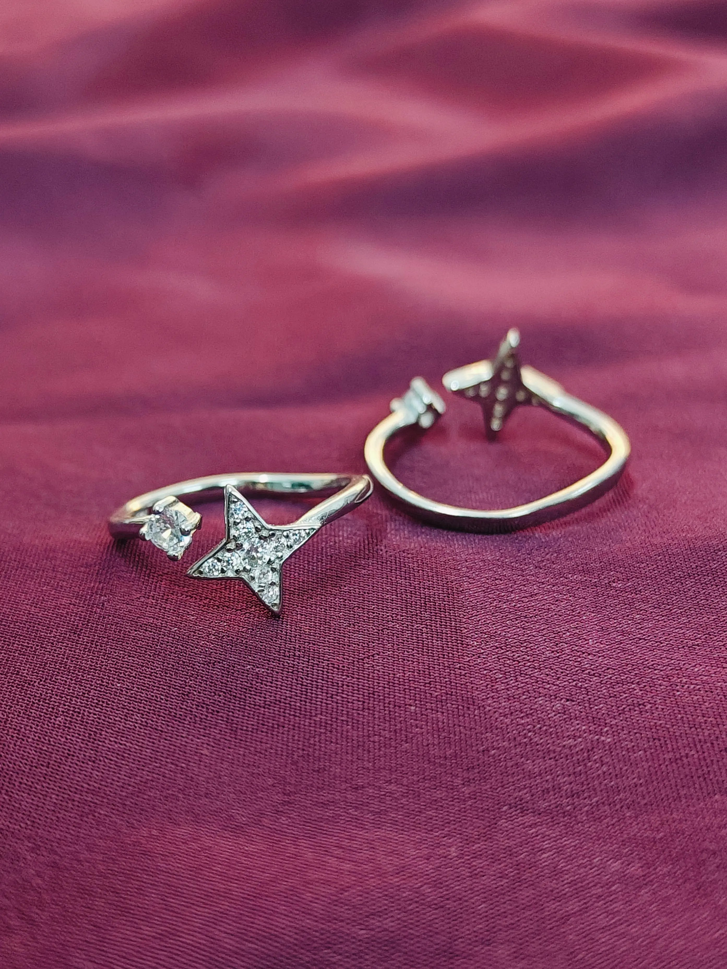 Two star-shaped rings on a textured red fabric background