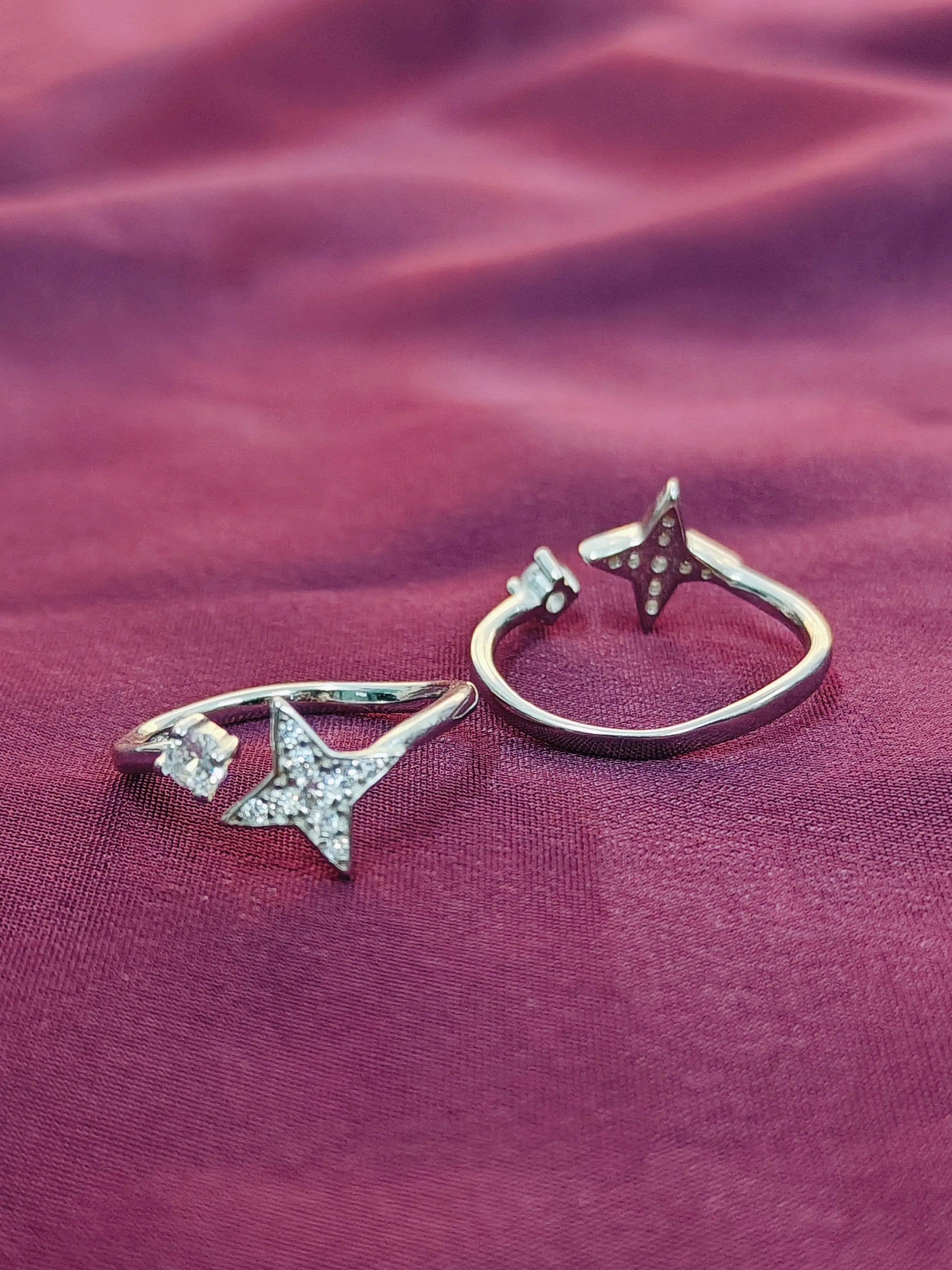 Two star-shaped rings on a purple fabric background