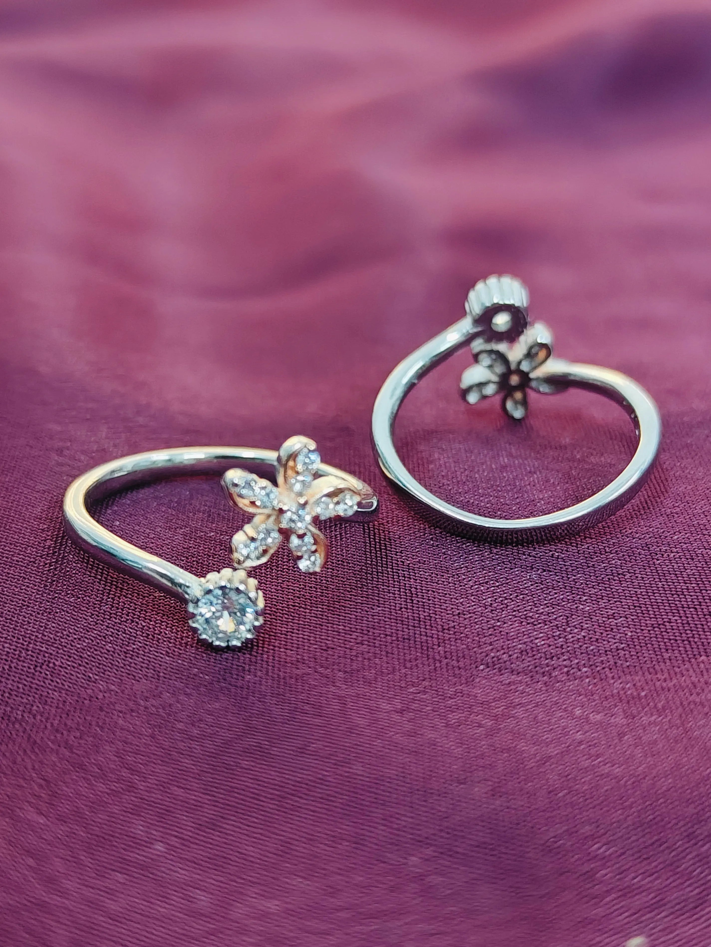 Two silver butterfly earrings on a purple fabric background