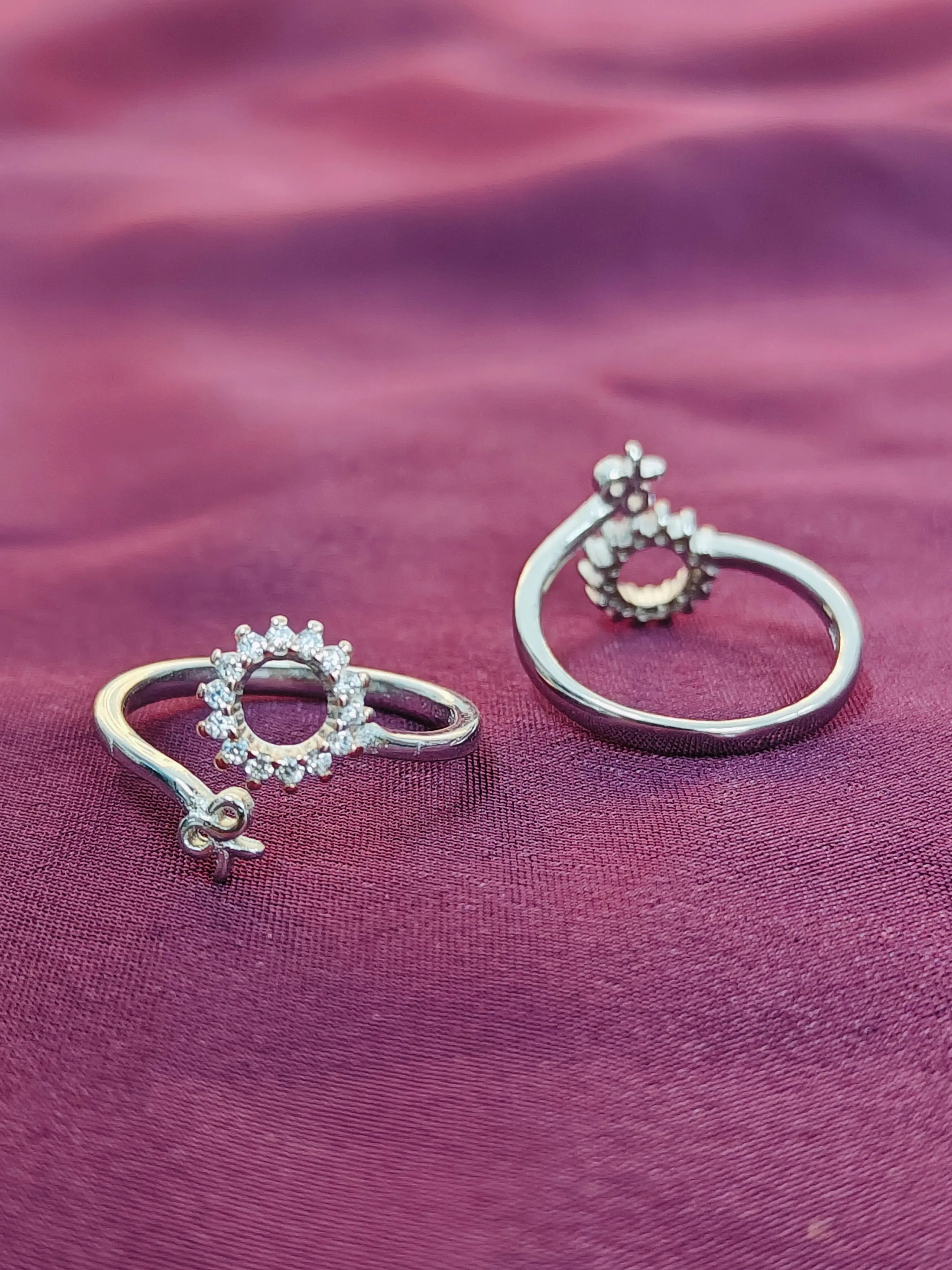 Two silver rings with gemstones on a purple fabric background