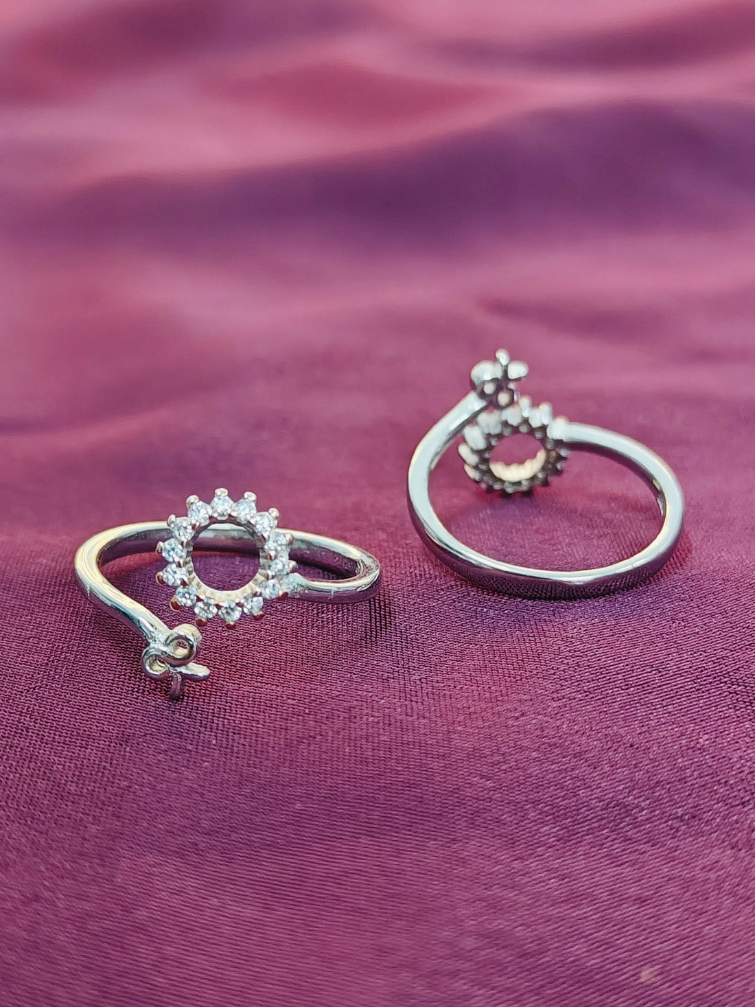 Two silver rings with gemstones on a purple fabric background