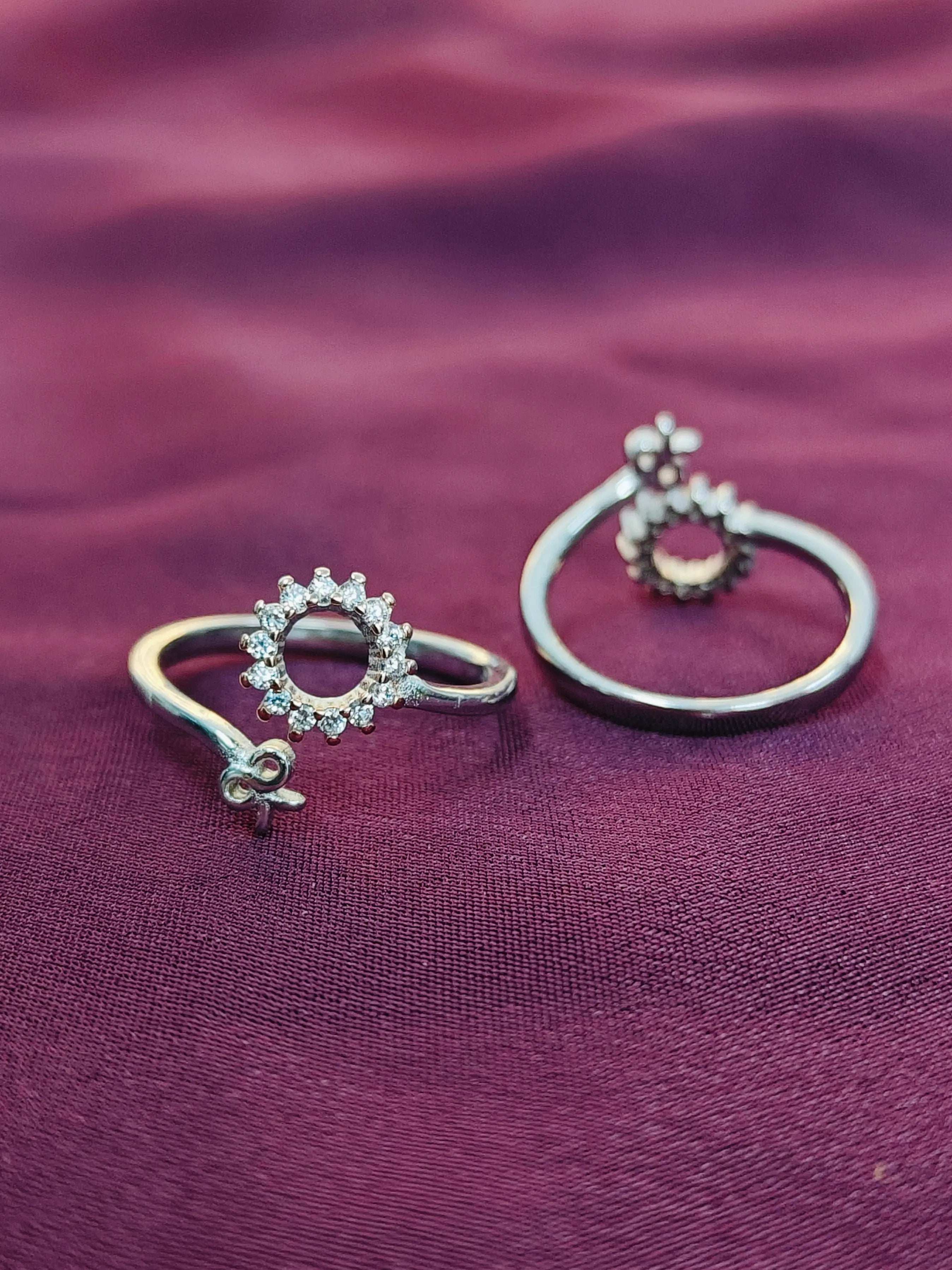 Two silver rings with floral designs on a purple fabric background