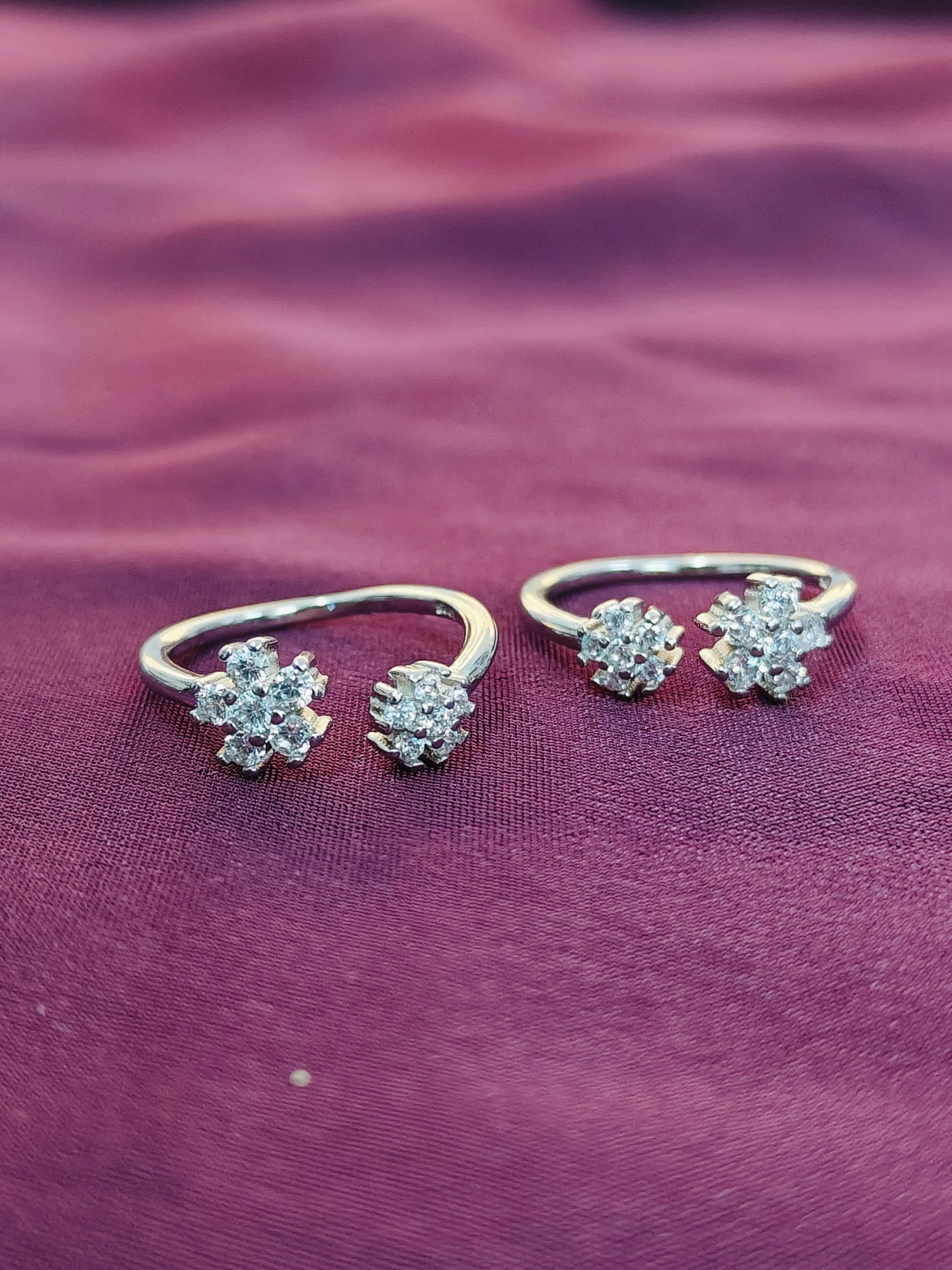 Silver ring with three diamond-like stones on a purple fabric background