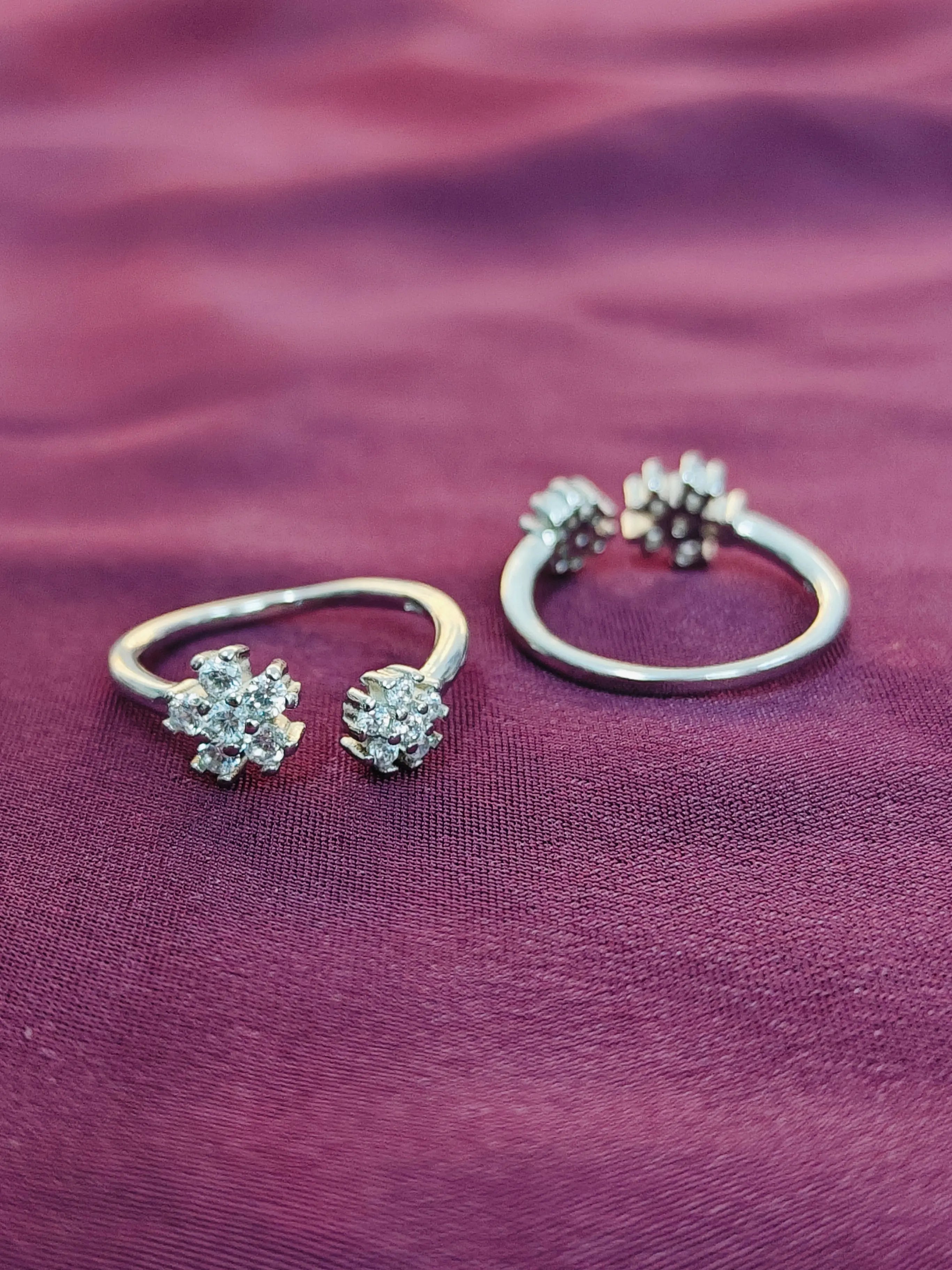 Pair of silver floral earrings on a purple fabric background