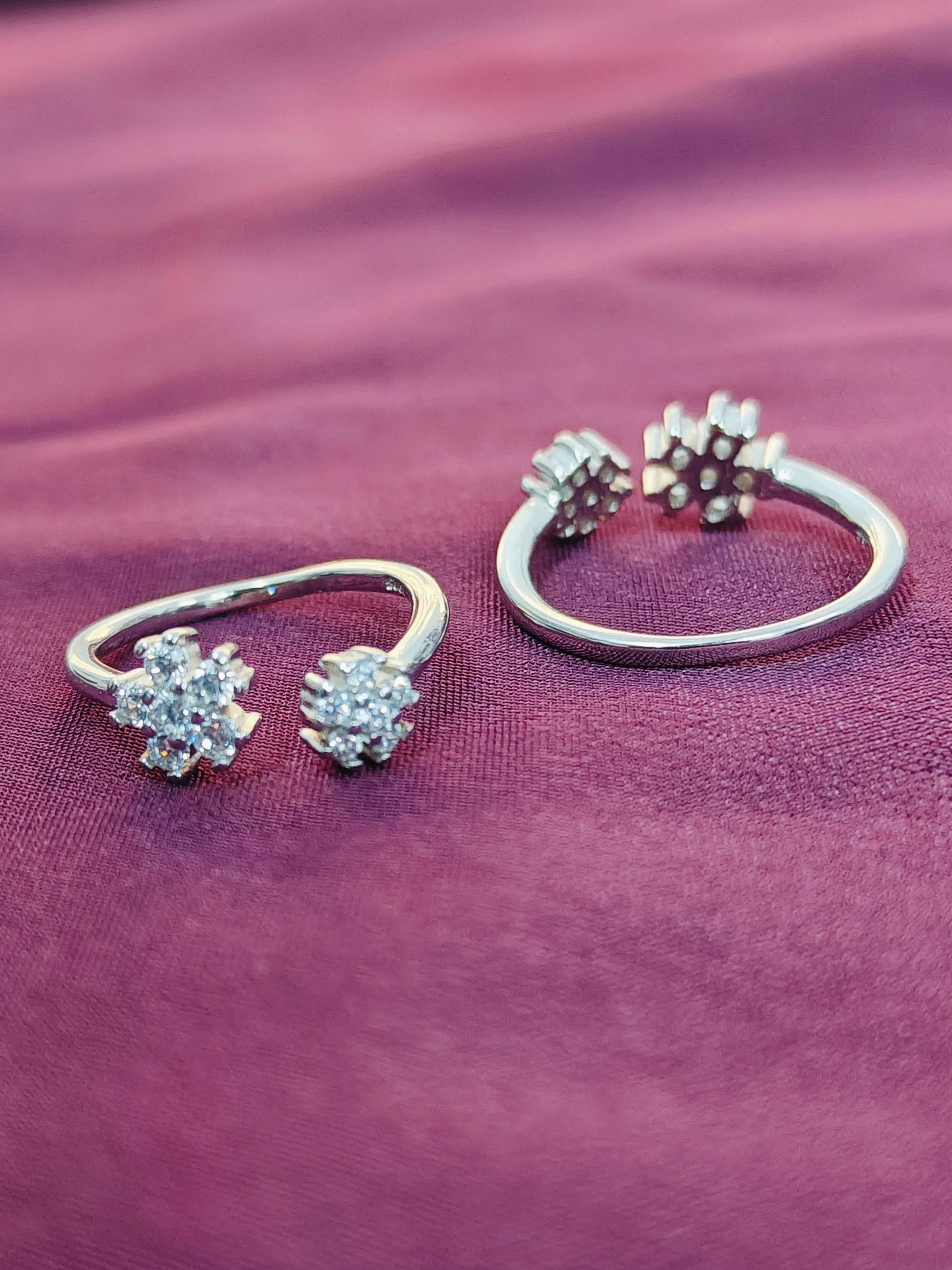 Silver hoop earrings with floral designs on a purple fabric background