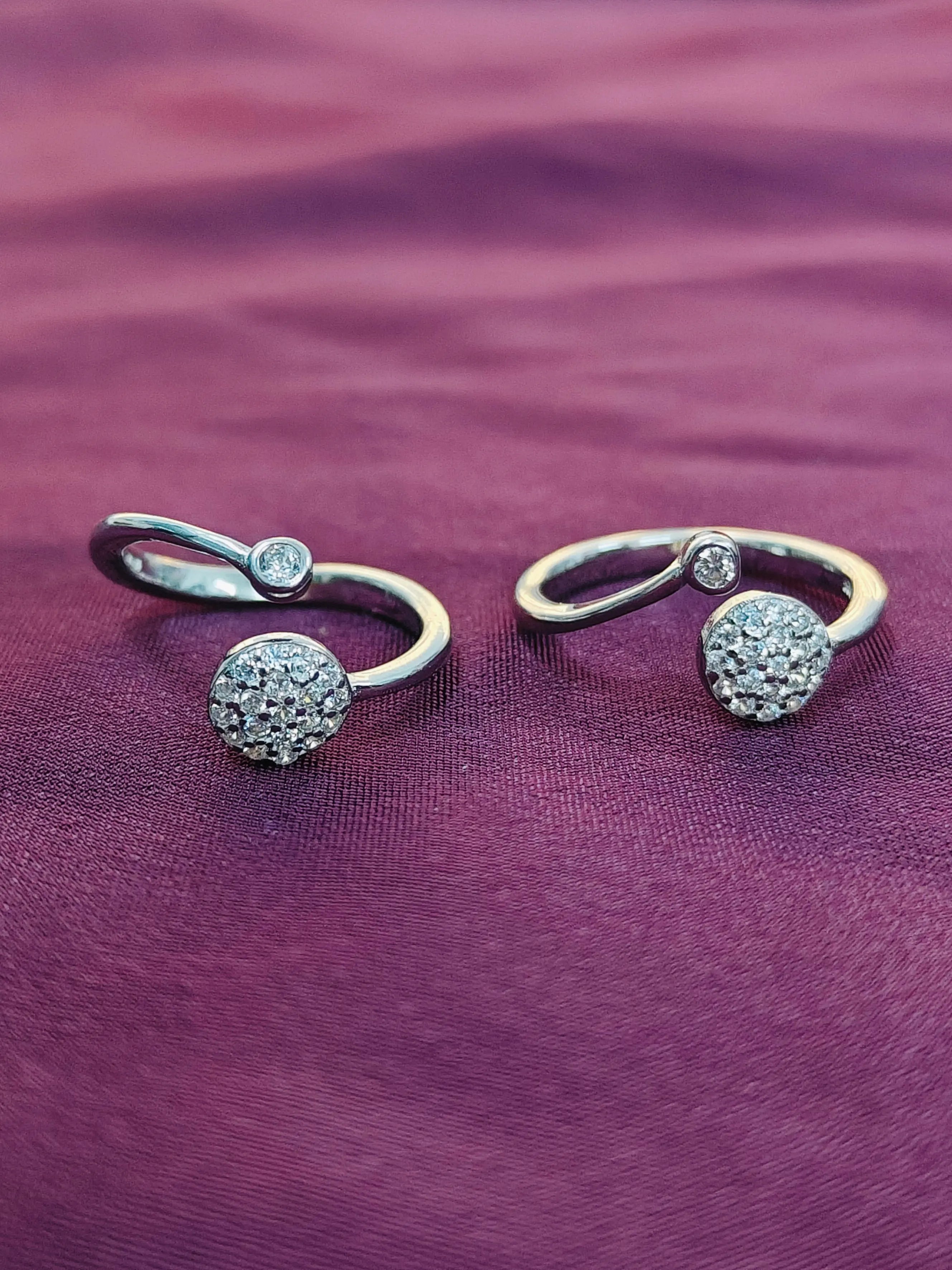 Two silver rings with gemstones on a purple fabric background