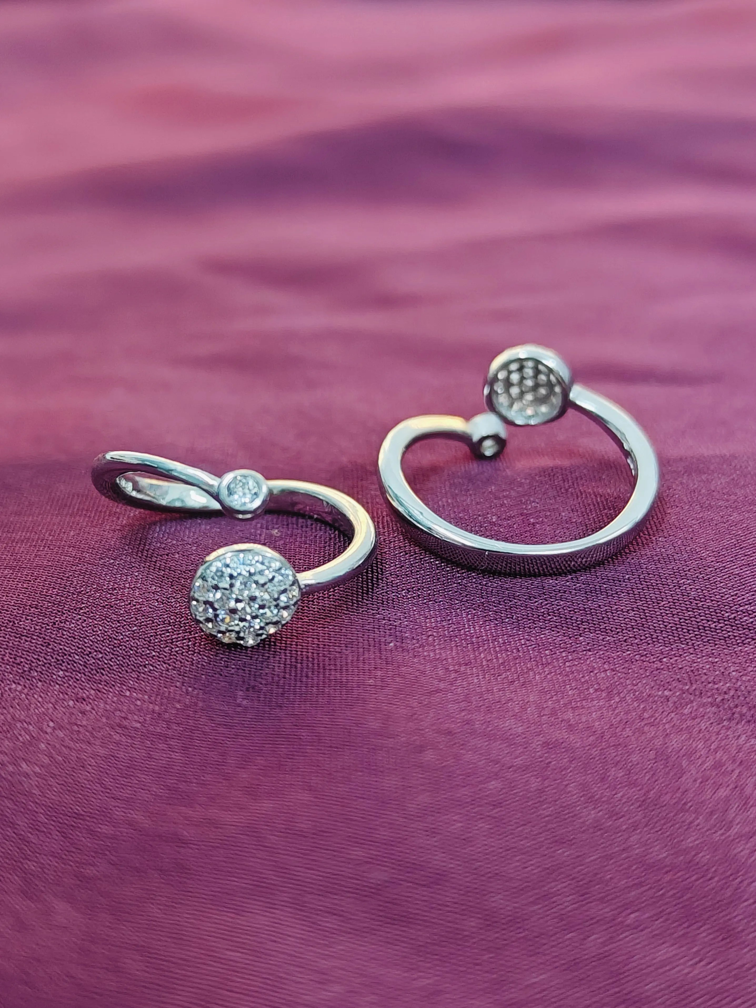 Two silver rings with textured ball designs on a purple fabric background