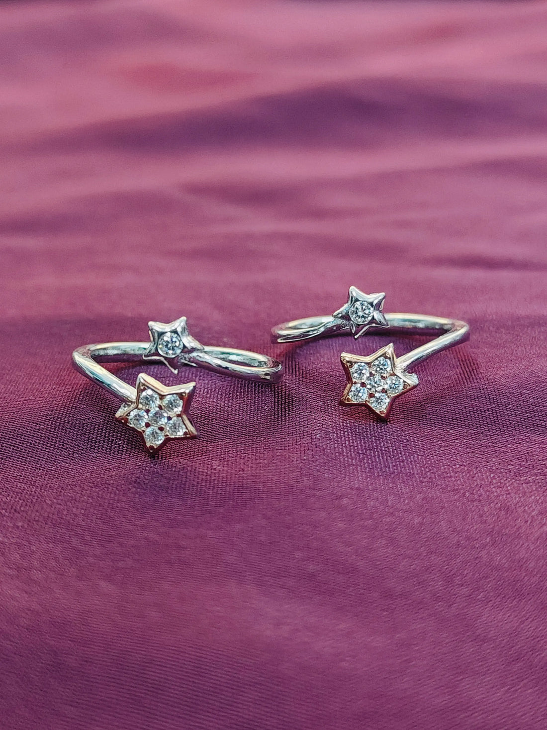 Star-shaped silver and gold rings on a purple fabric background