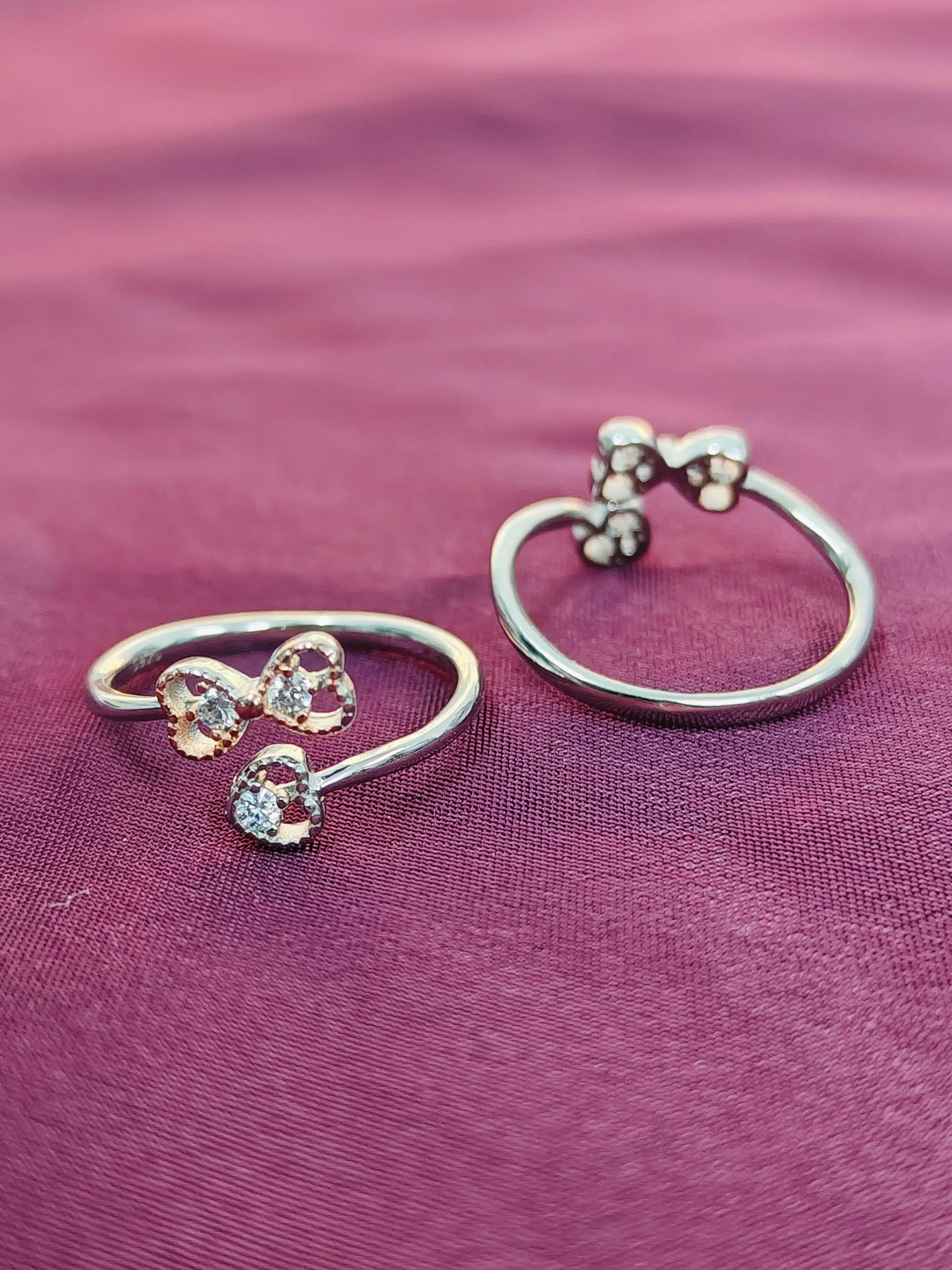 Two open rings with bow designs on a purple fabric background