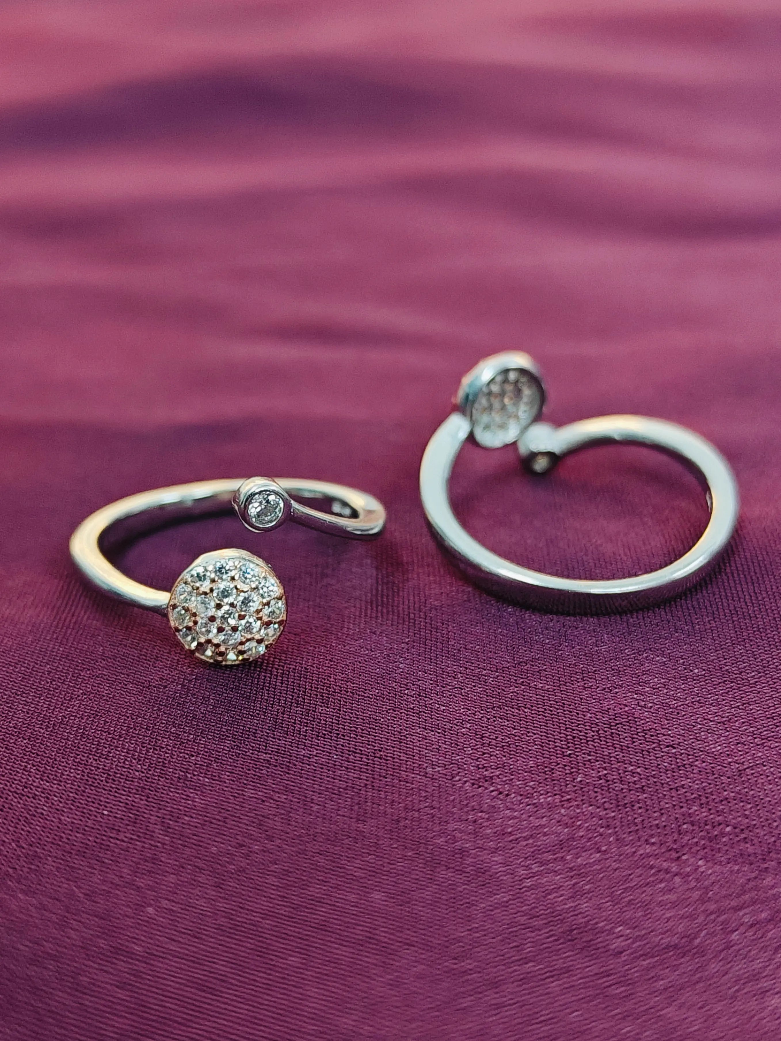 Two silver rings with ball designs on a purple fabric background