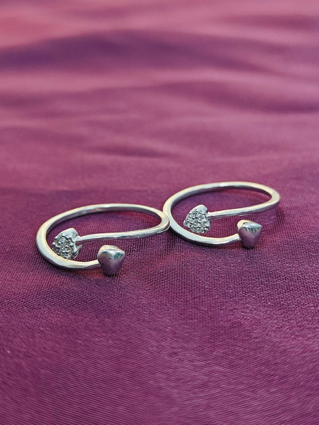 Set of silver open rings with heart-shaped embellishments on a purple fabric background