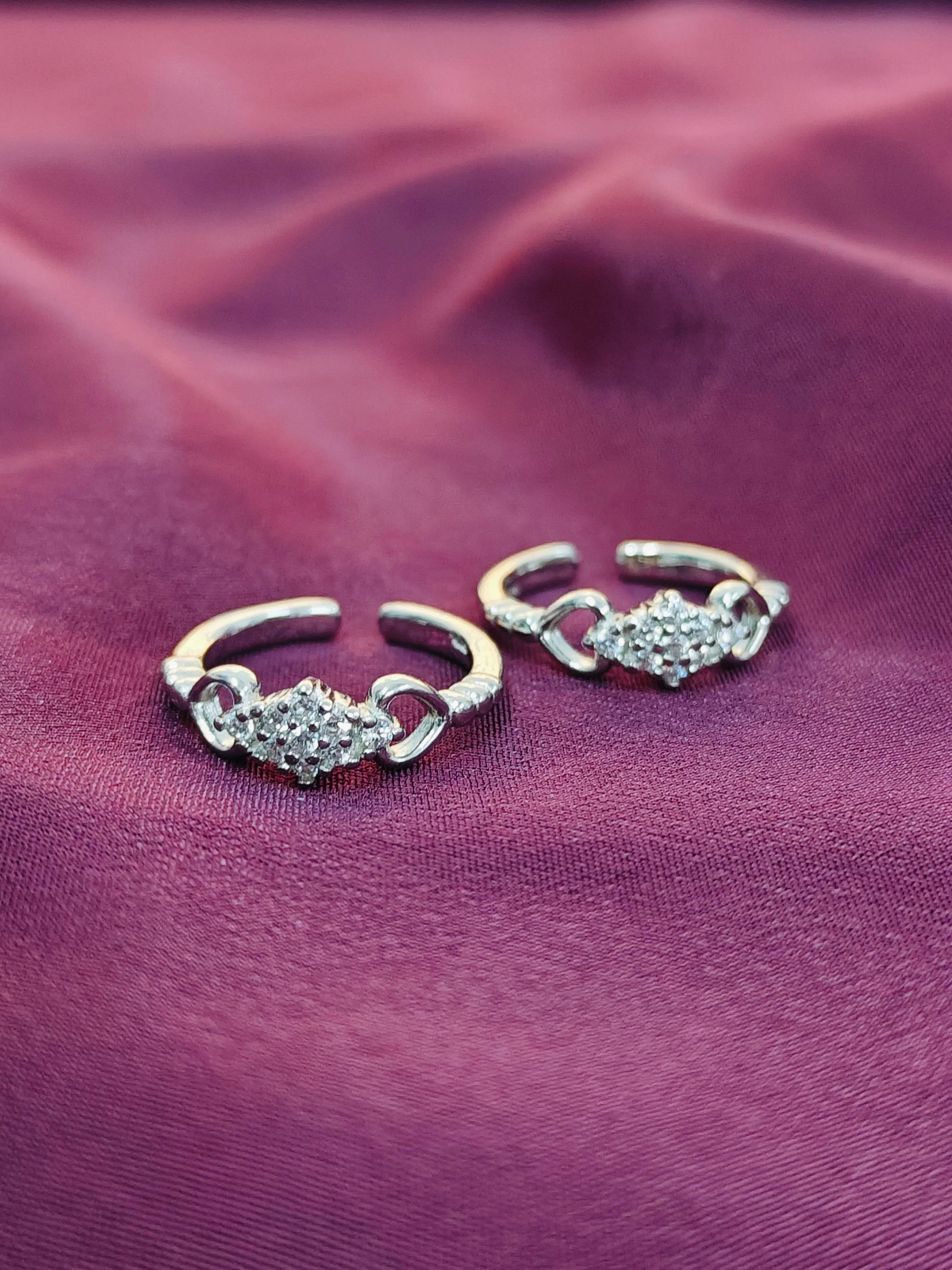 Two gold and diamond ear cuffs on a purple fabric background