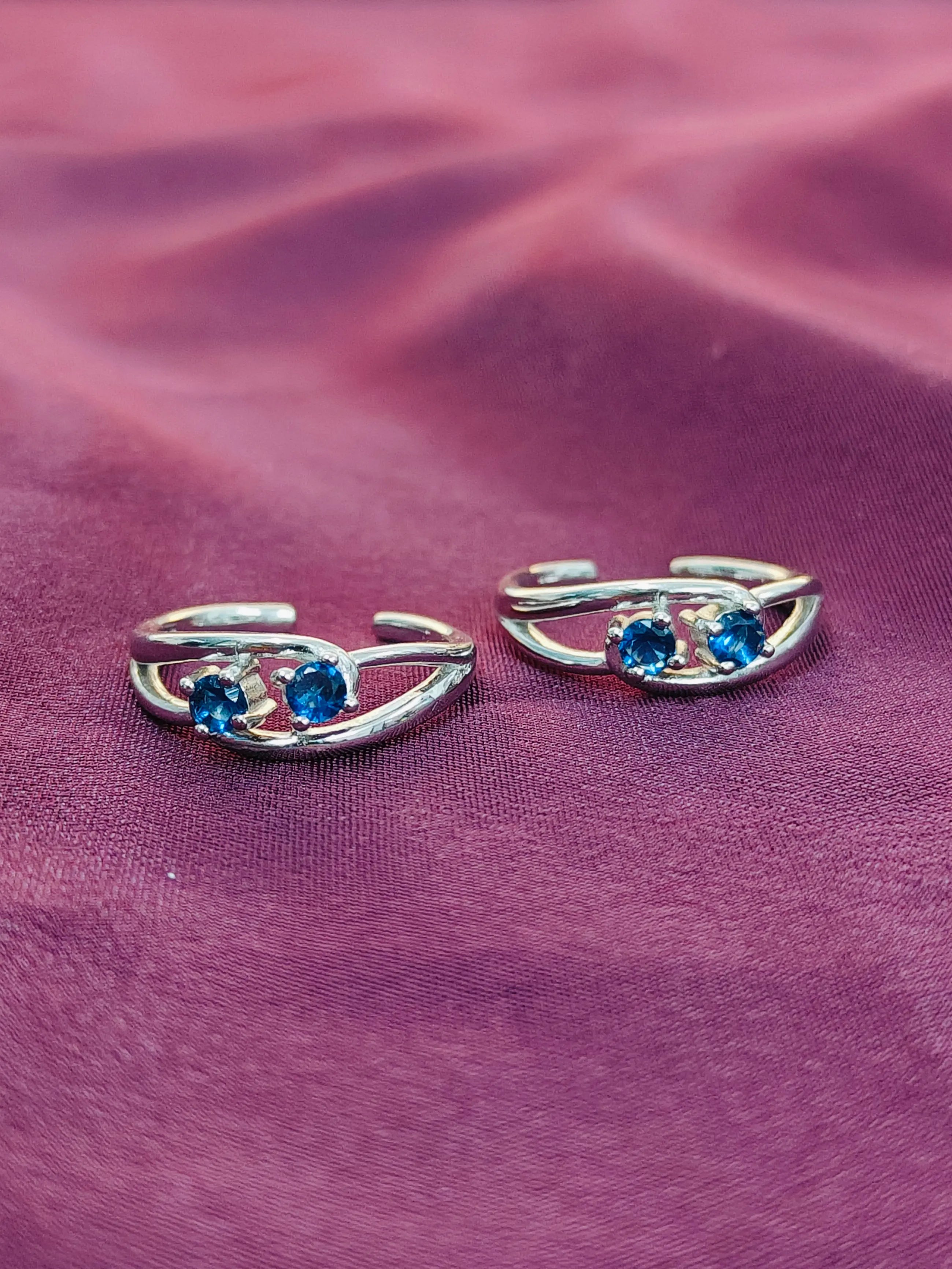 Silver earrings with blue gemstones on a purple fabric background