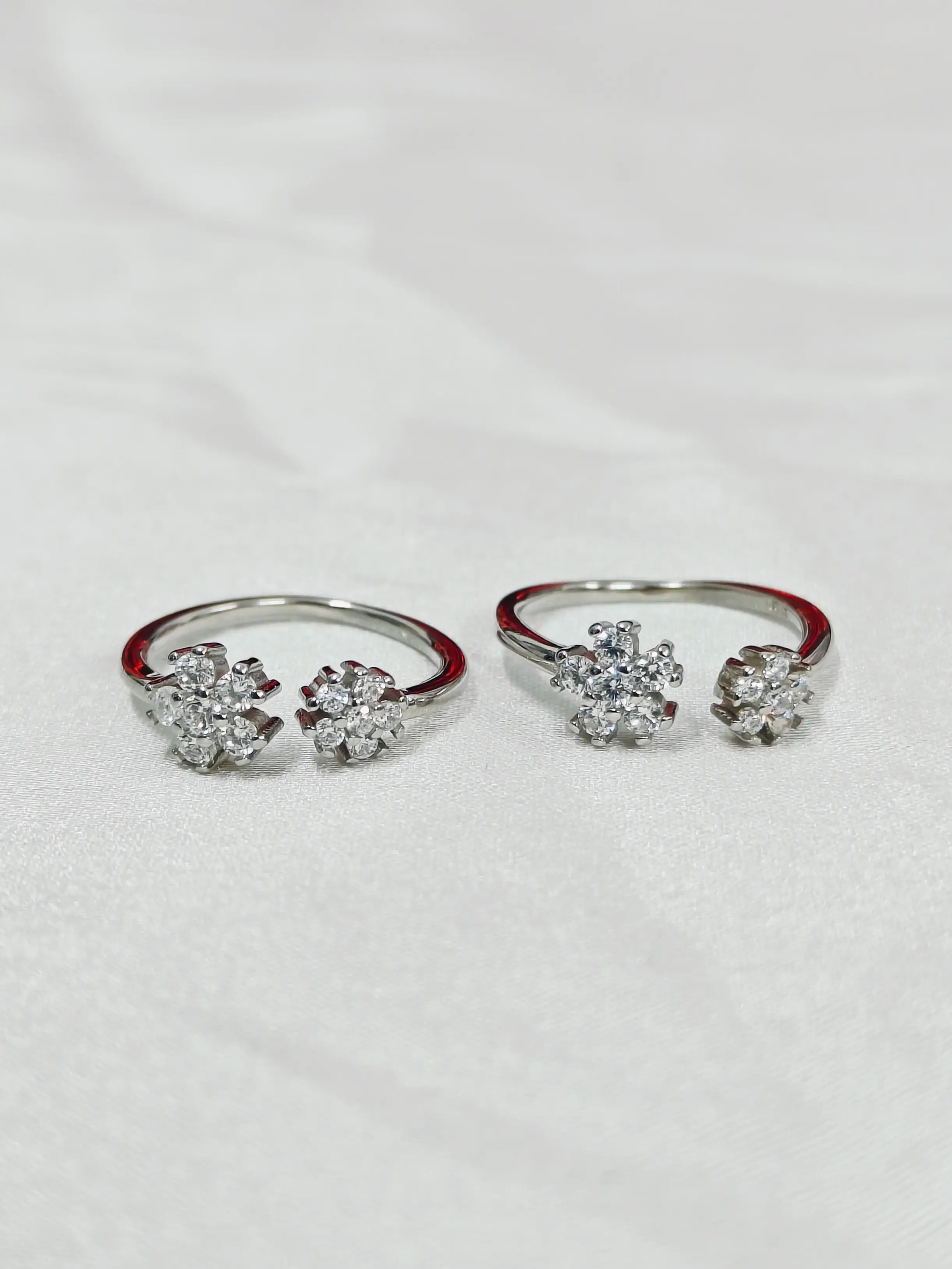Pair of silver rings with floral designs on a white background