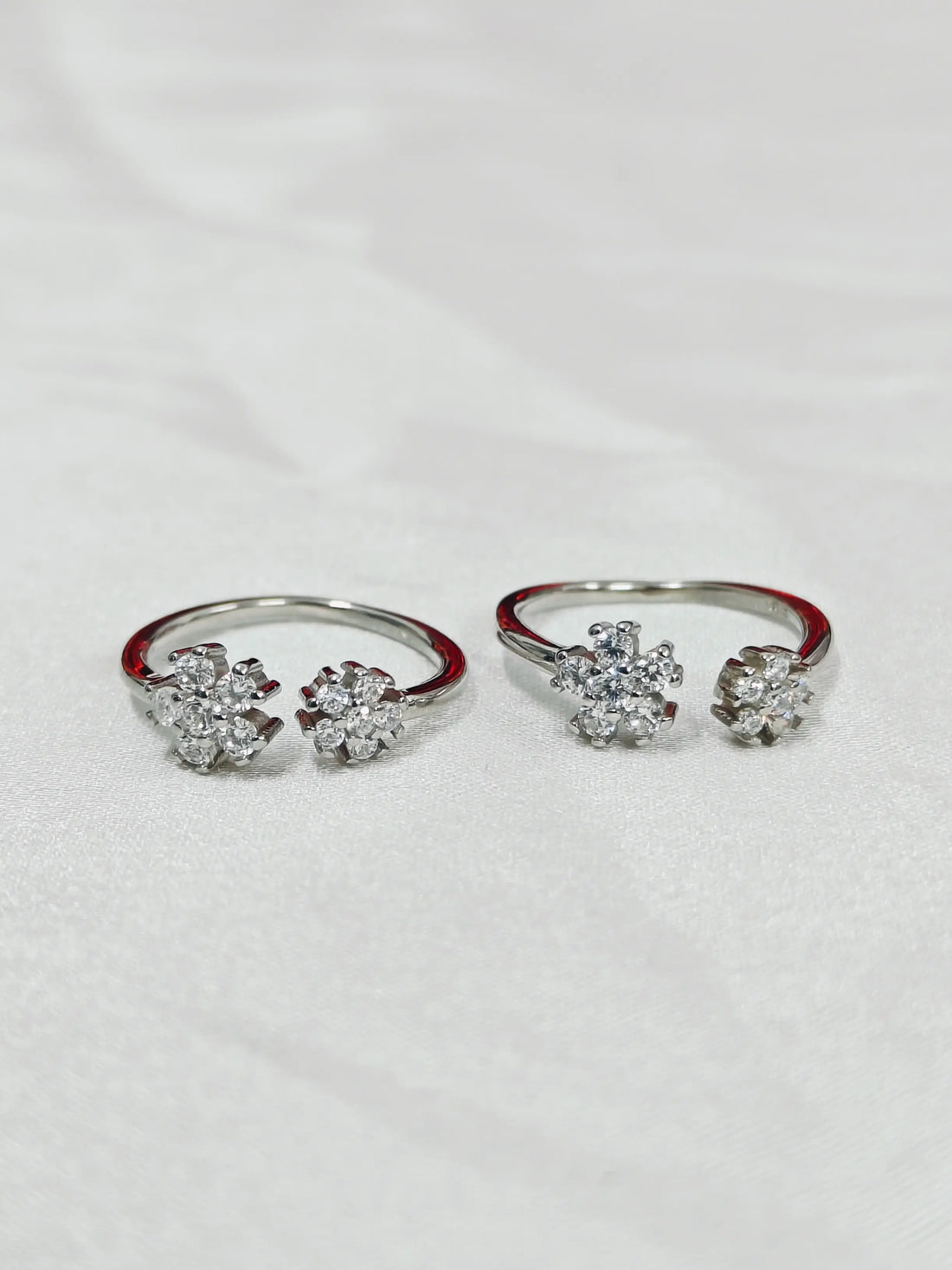 Pair of silver rings with floral designs on a white background